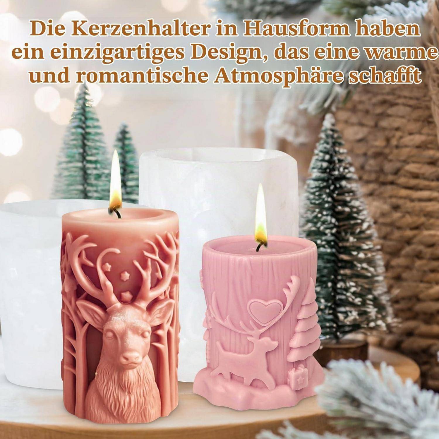 Zwei dekorative hausförmige Kerzen mit Hirschdesigns und brennenden Flammen, gezeigt auf einer Holzoberfläche mit einer weißen Kerze dahinter und kleinen Weihnachtsbäumen im Hintergrund.