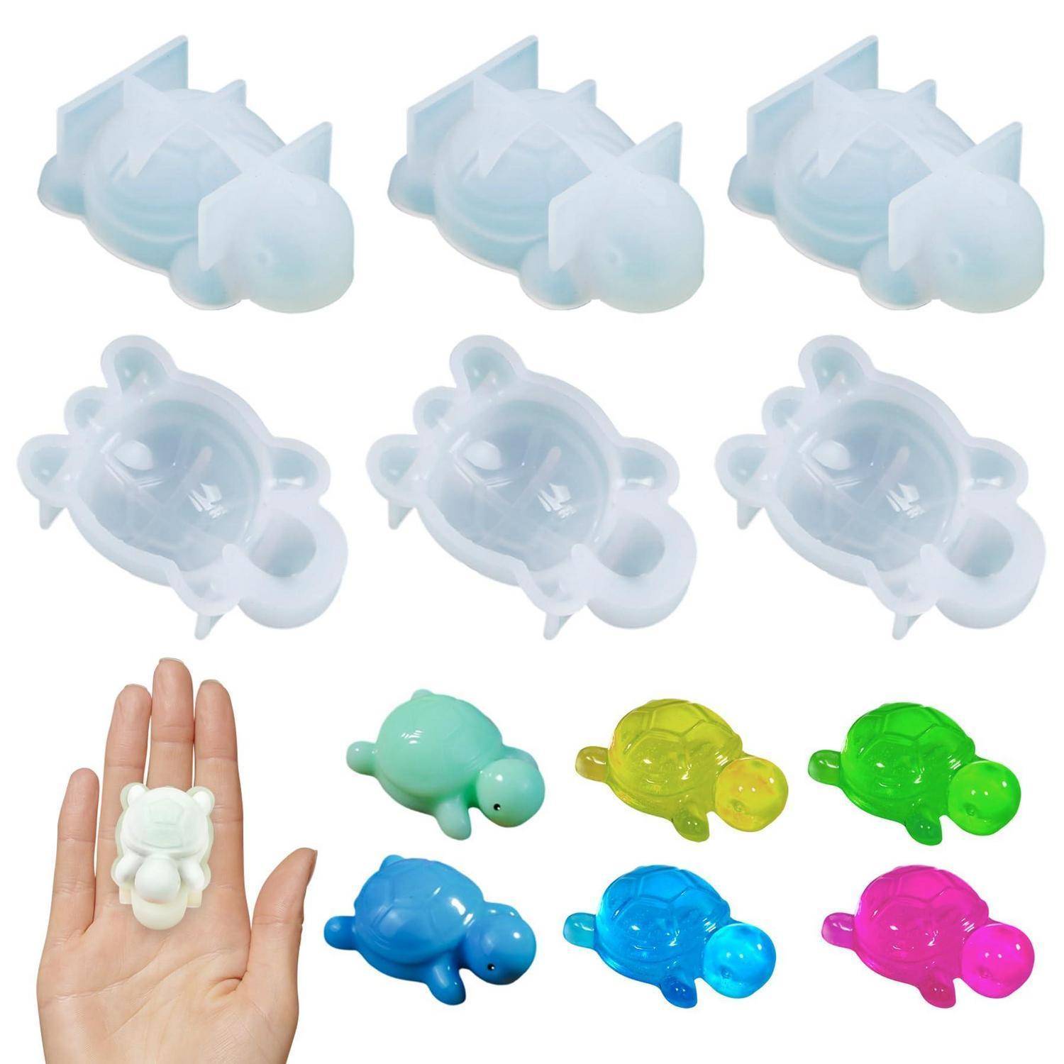 Assortierte schildkrötenförmige Silikonformen und farbenfrohe fertige Mini-Schildkröten-Bonbons oder Seifen auf weißem Hintergrund, wobei eine Form in einer Hand zur Größenangabe gezeigt wird.