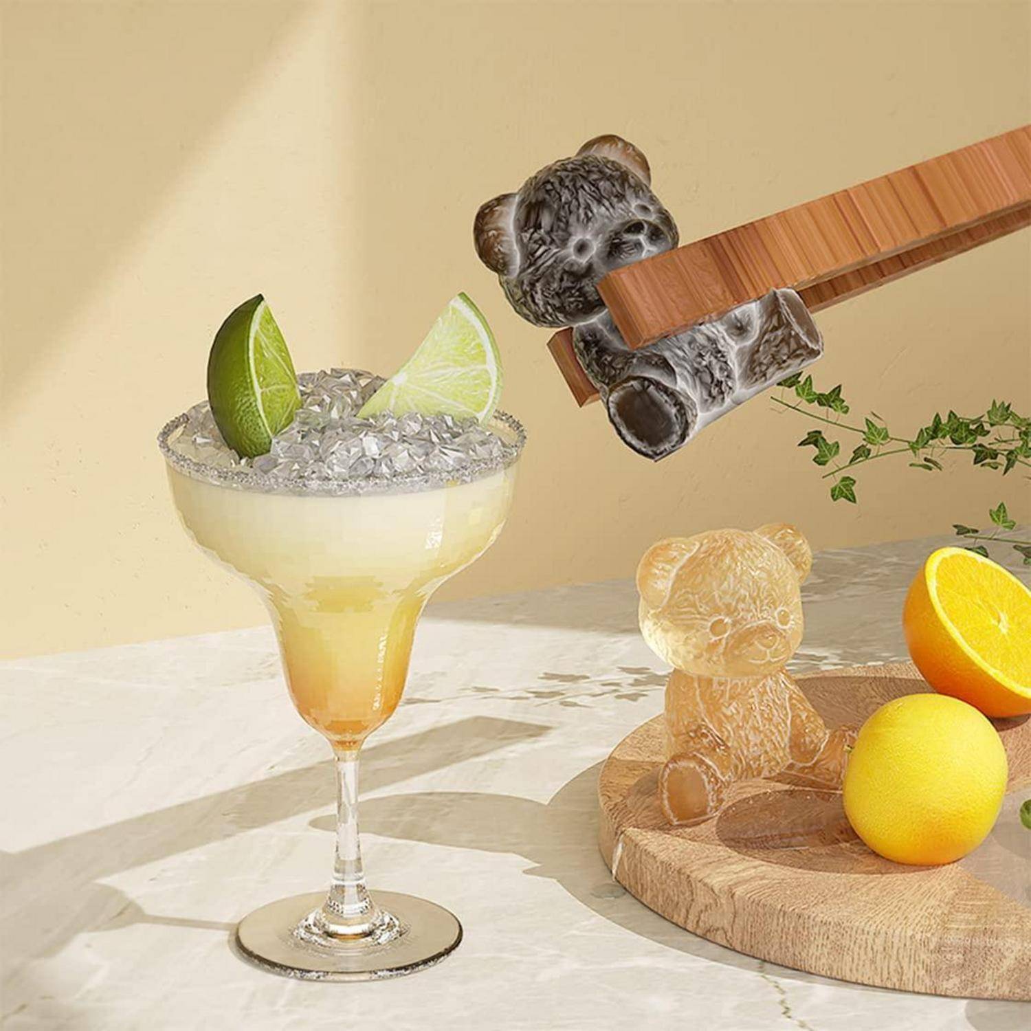 Cocktailglas mit Limettenscheiben und Eis neben einem Holzbrett mit Zitrusfrüchten, einem kleinen Teddybär und einem bärenförmigen Essstäbchenhalter.
