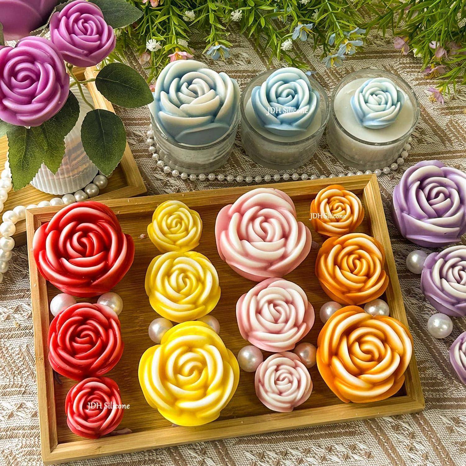 Tablett mit farbenfrohen rosenförmigen Cupcakes oder Desserts in Rot, Gelb, Rosa, Orange, Blau und Lila, angeordnet auf dekorativen Tellern mit Perlen und Blumen.