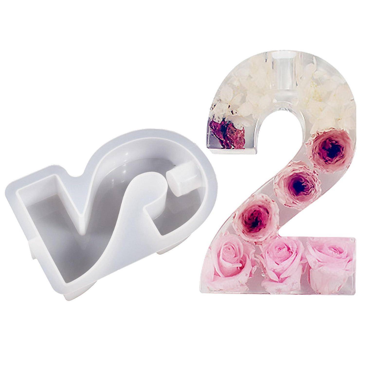 Herzförmige Silikonform und fertige Nummer 2 verziert mit rosa und weißen Blumen, was auf ein selbstgemachtes Harz- oder Kuchendekorierset hindeutet.