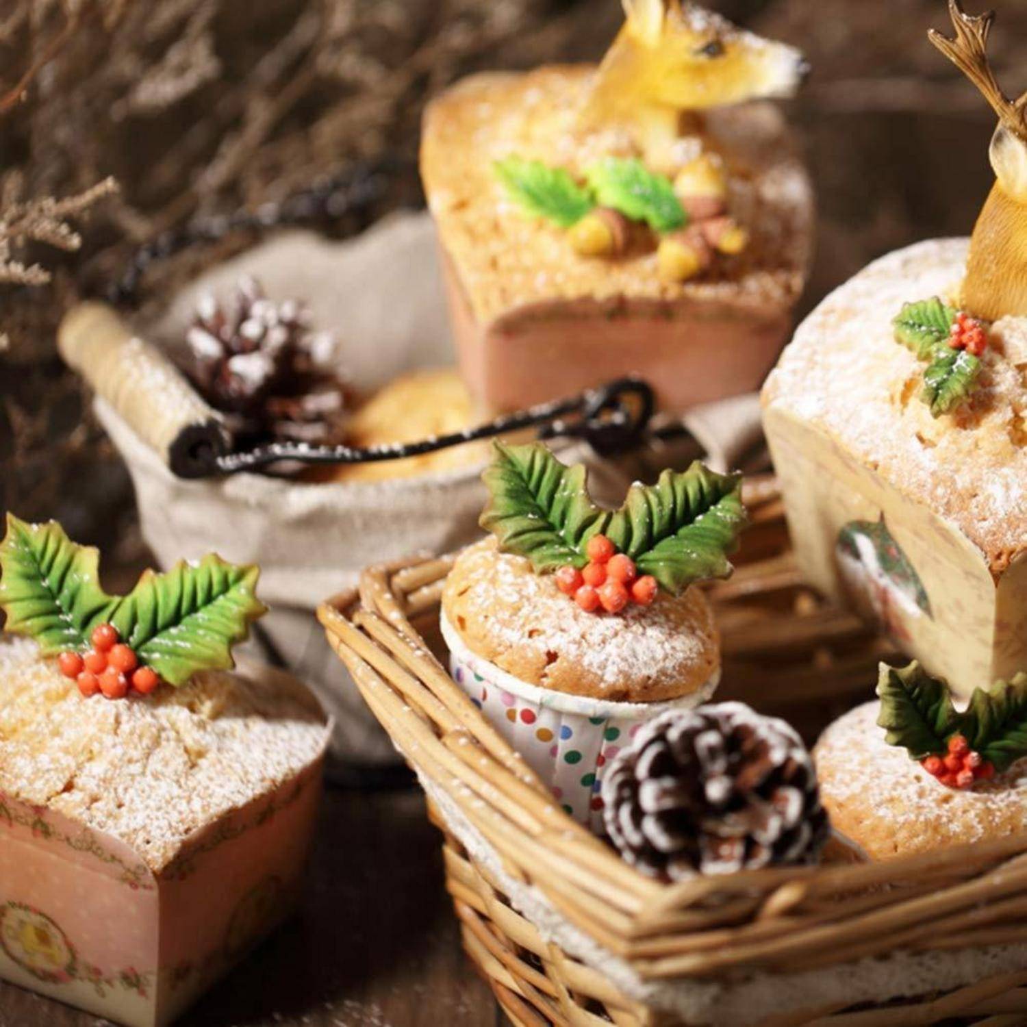 Festliche Weihnachtsdessertboxen mit Puderzucker bestreut, Stechpalmendekorationen und Tannenzapfen in einem Weidenkorb