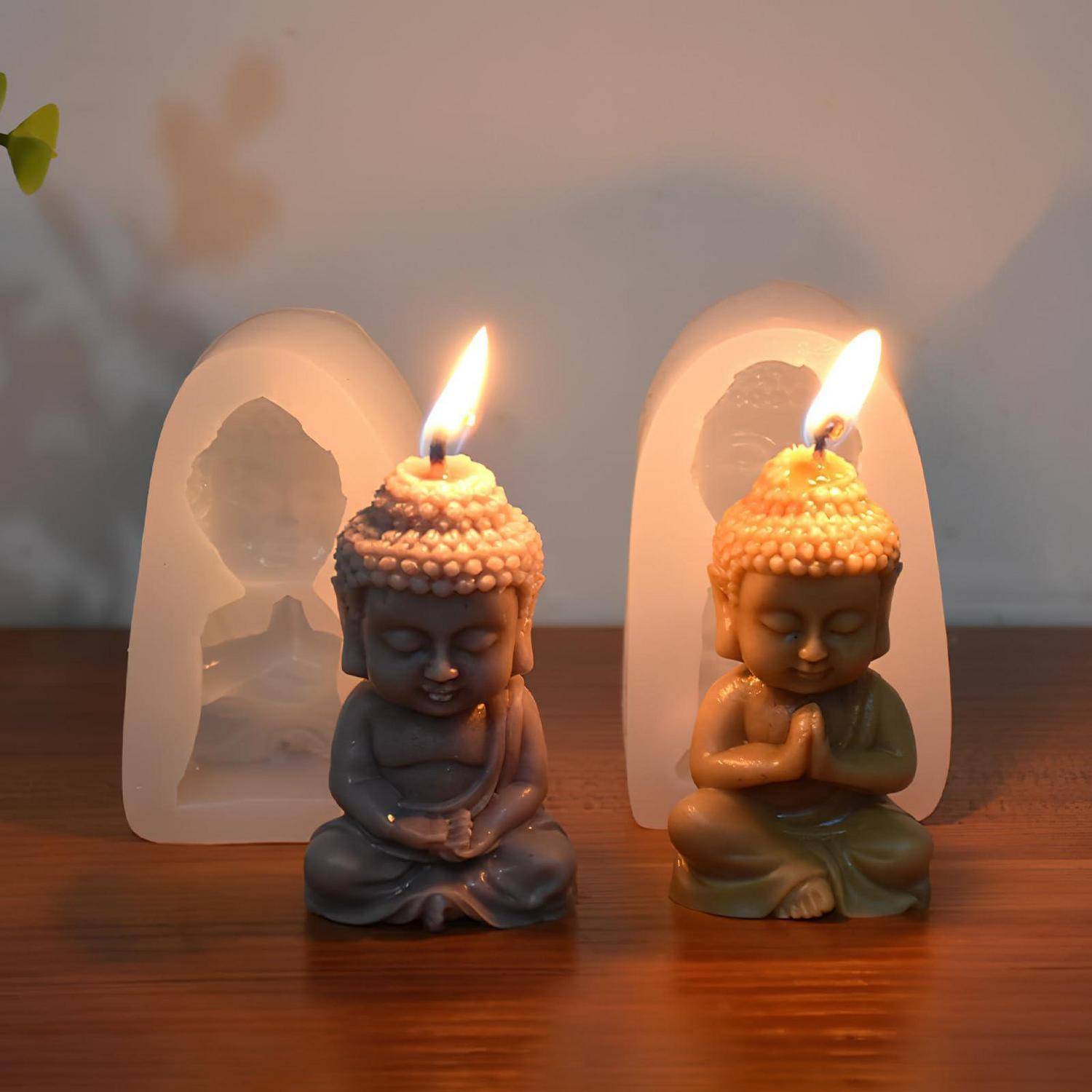 Zwei leuchtende Buddha-förmige Kerzen stehen auf einer Holzoberfläche vor durchscheinenden gewölbten Haltern mit Buddha-Silhouetten.