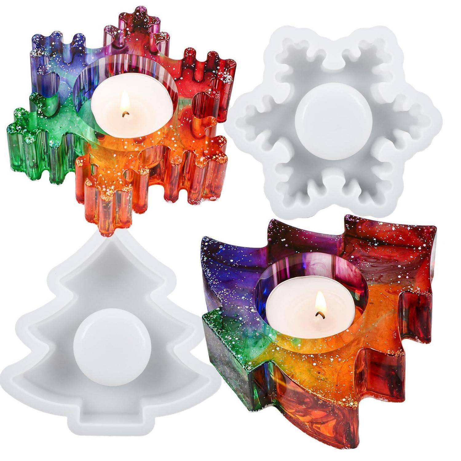 Vier dekorative Kerzenhalter: zwei regenbogenfarbene Glitter-Zahnradformen und zwei weiße Baumformen, jeweils mit einer zentralen Kerzenmuschel.