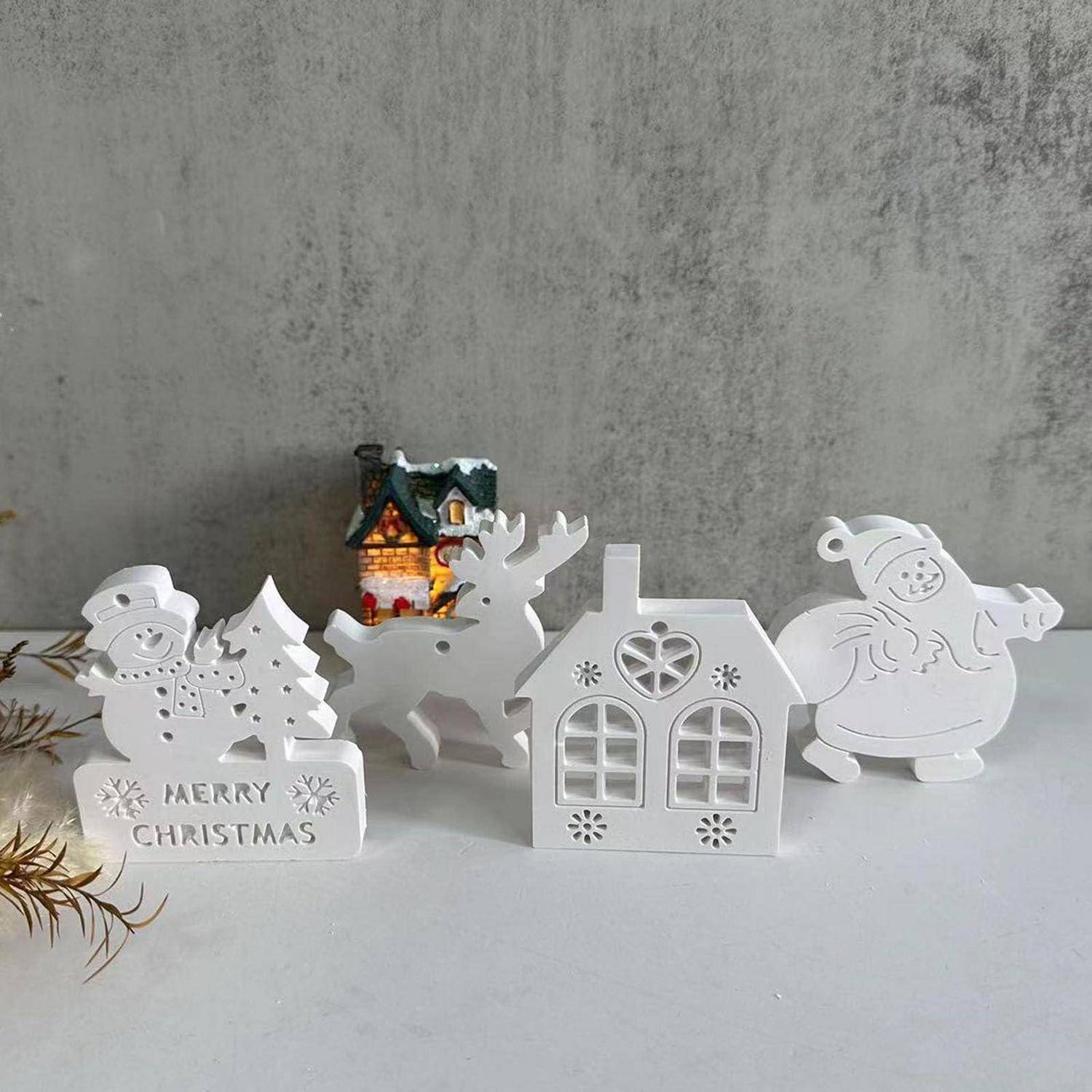 Weihnachtliche Tischdekoration im Winter-Design: Schneemann mit „FROHE WEIHNACHTEN"-Schild, Rentier, Haus und Weihnachtsmann im Schlitten rund um ein kleines beleuchtetes Häuschen.