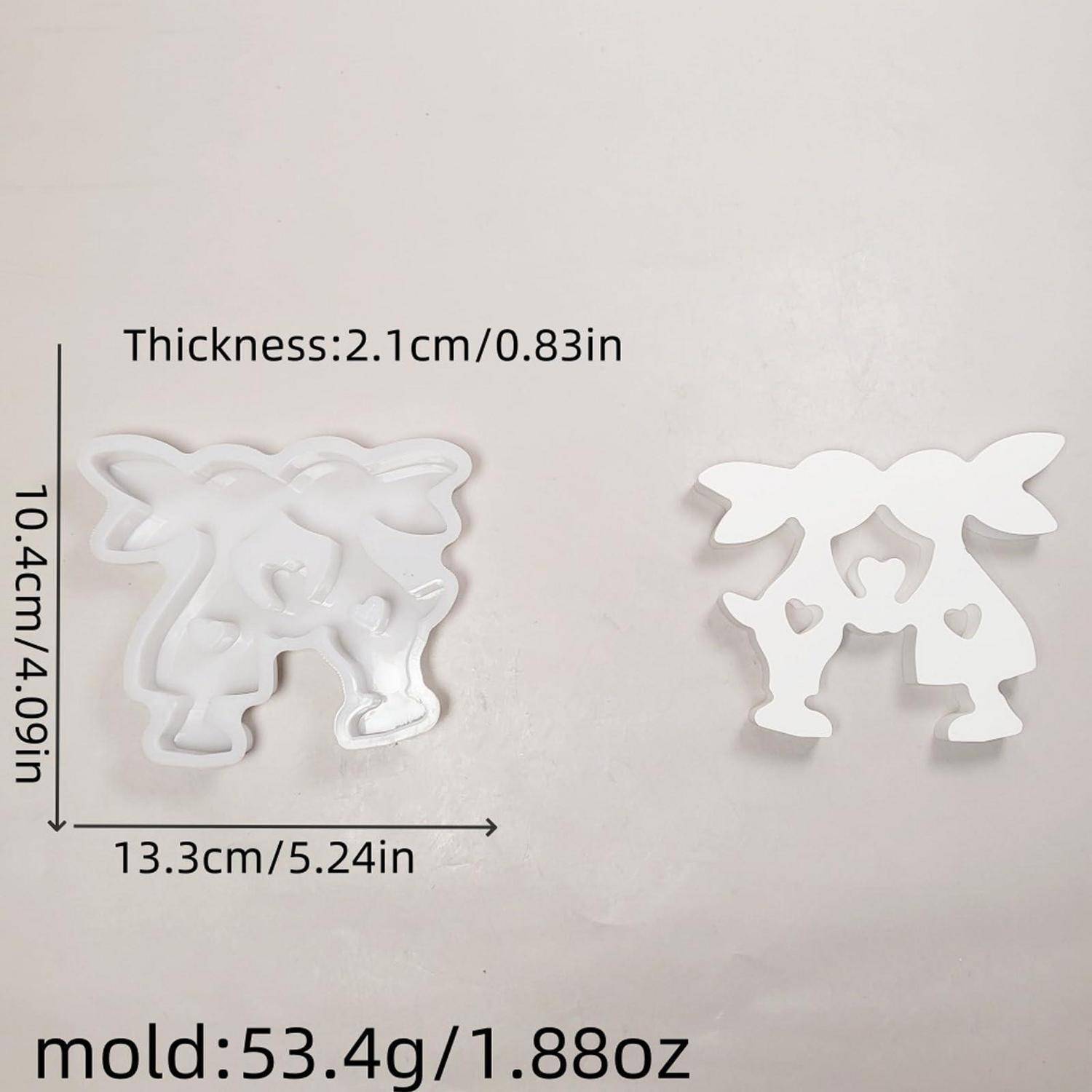 Weiße Form oder Ausstecher in stilisierter Kuhform, von vorne und hinten gezeigt, mit bezeichneter Größe 13,3 x 10,4 cm und Dicke 2,1 cm.