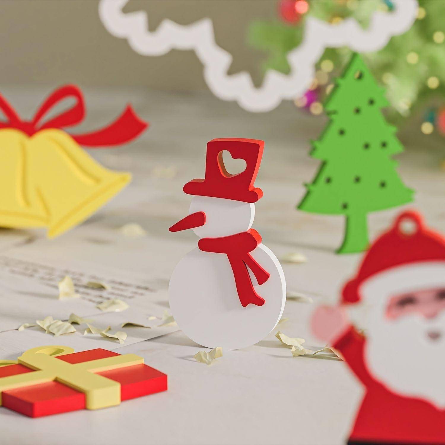 Festliche Weihnachtsszene mit einer Papierschneemann-Tischdekoration, umgeben von einer Glocke, einem Baum, einem Geschenk und Weihnachtsmanndekorationen auf einer Tischplatte.