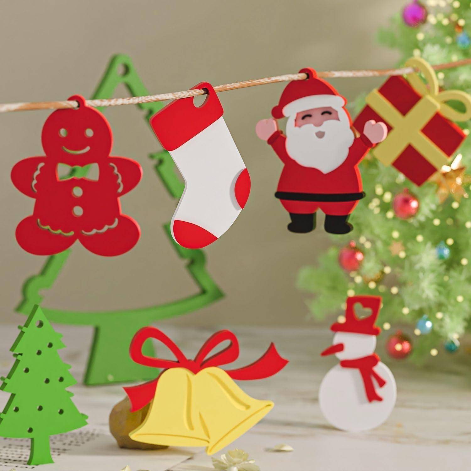 Weihnachtsdekorationen an einer Schnur: Lebkuchenmann, Strumpf, Weihnachtsmann und Geschenk mit einem Baum, Glocken und Schneemann in der Nähe eines geschmückten Weihnachtsbaums.