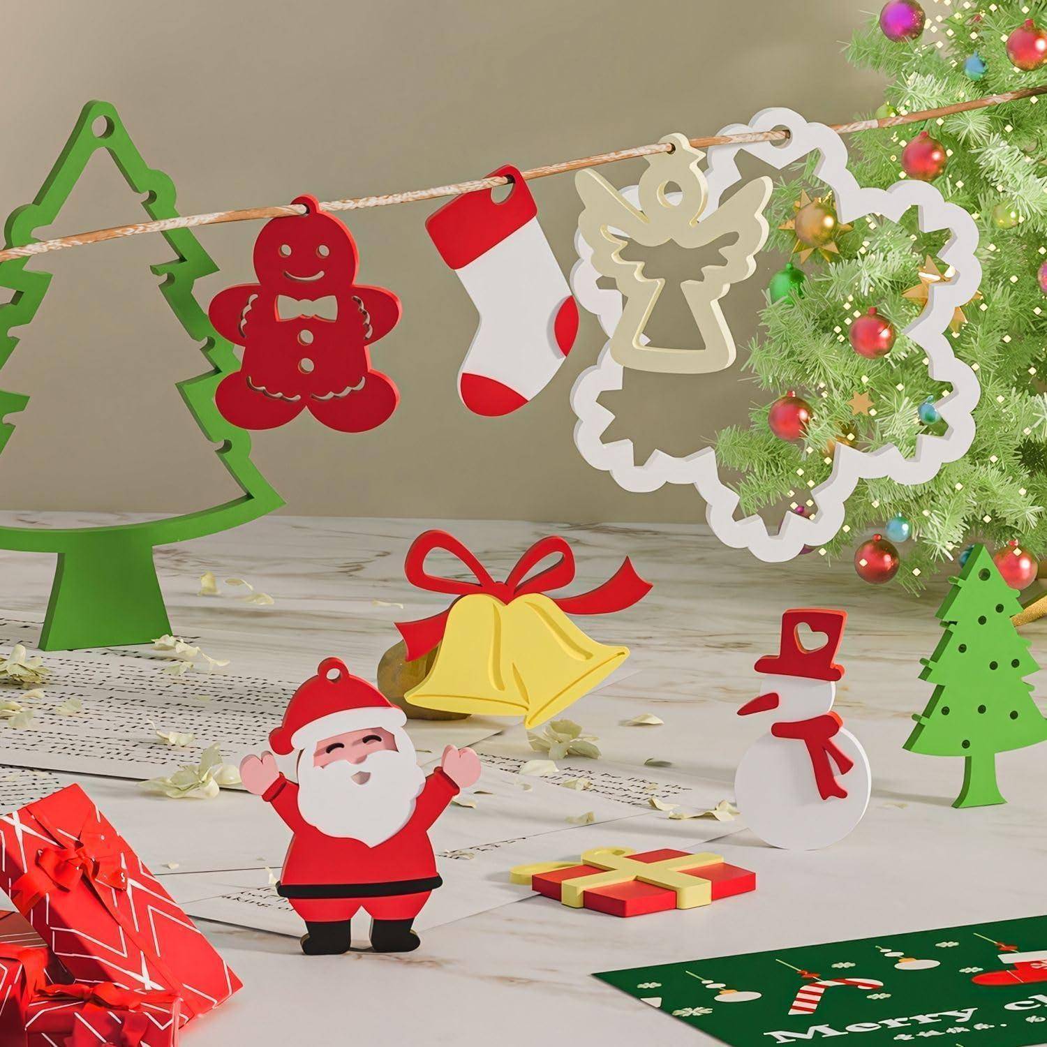 Festliche Weihnachtsbastlszene mit hängenden Verzierungen, einem geschmückten Baum, dem Weihnachtsmann, einem Schneemann, Glocken und Geschenkboxen auf einer Tischplatte.