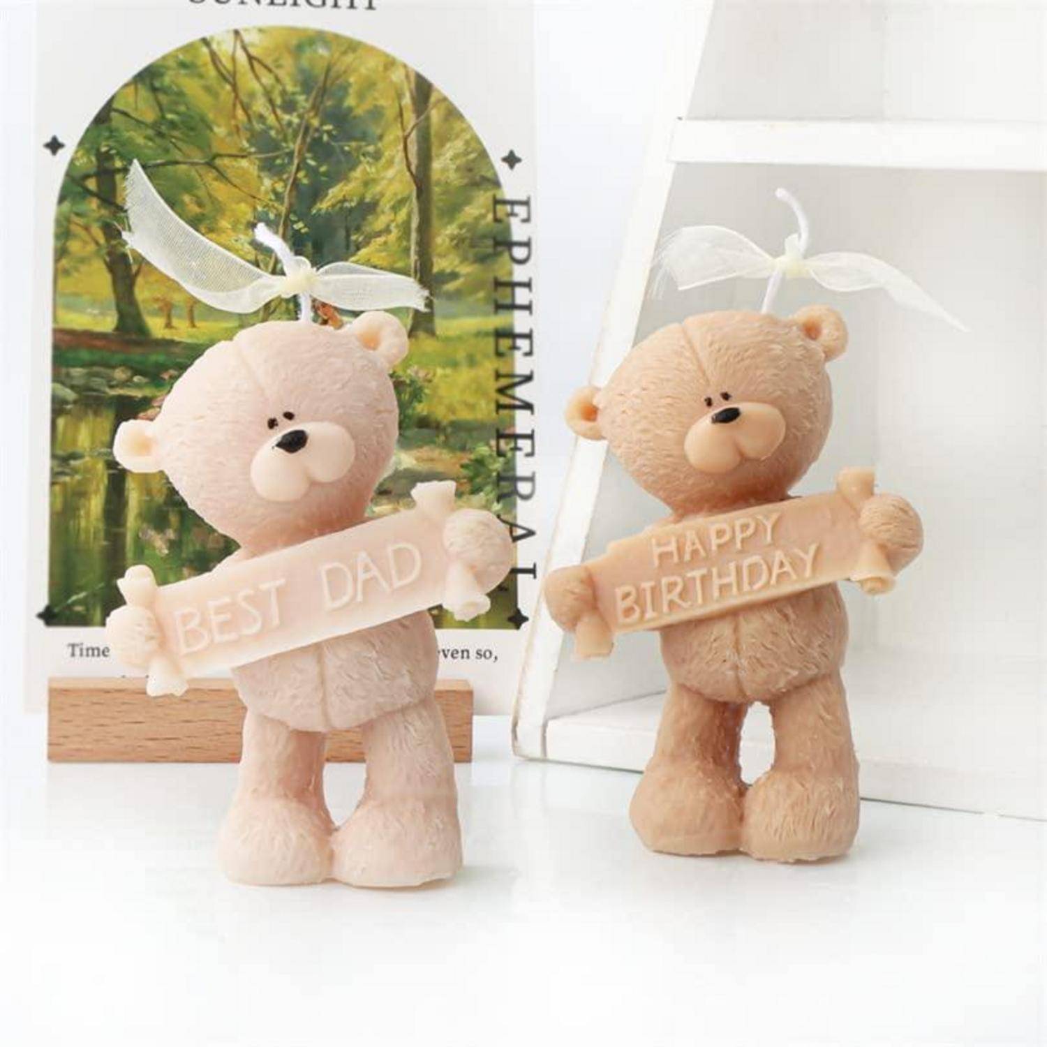 Zwei Teddybär-Figuren halten Schilder mit den Aufschriften "BEST DAD"" und ""HAPPY BIRTHDAY"" auf einer weißen Oberfläche mit einem eingerahmten Bild dahinter.
