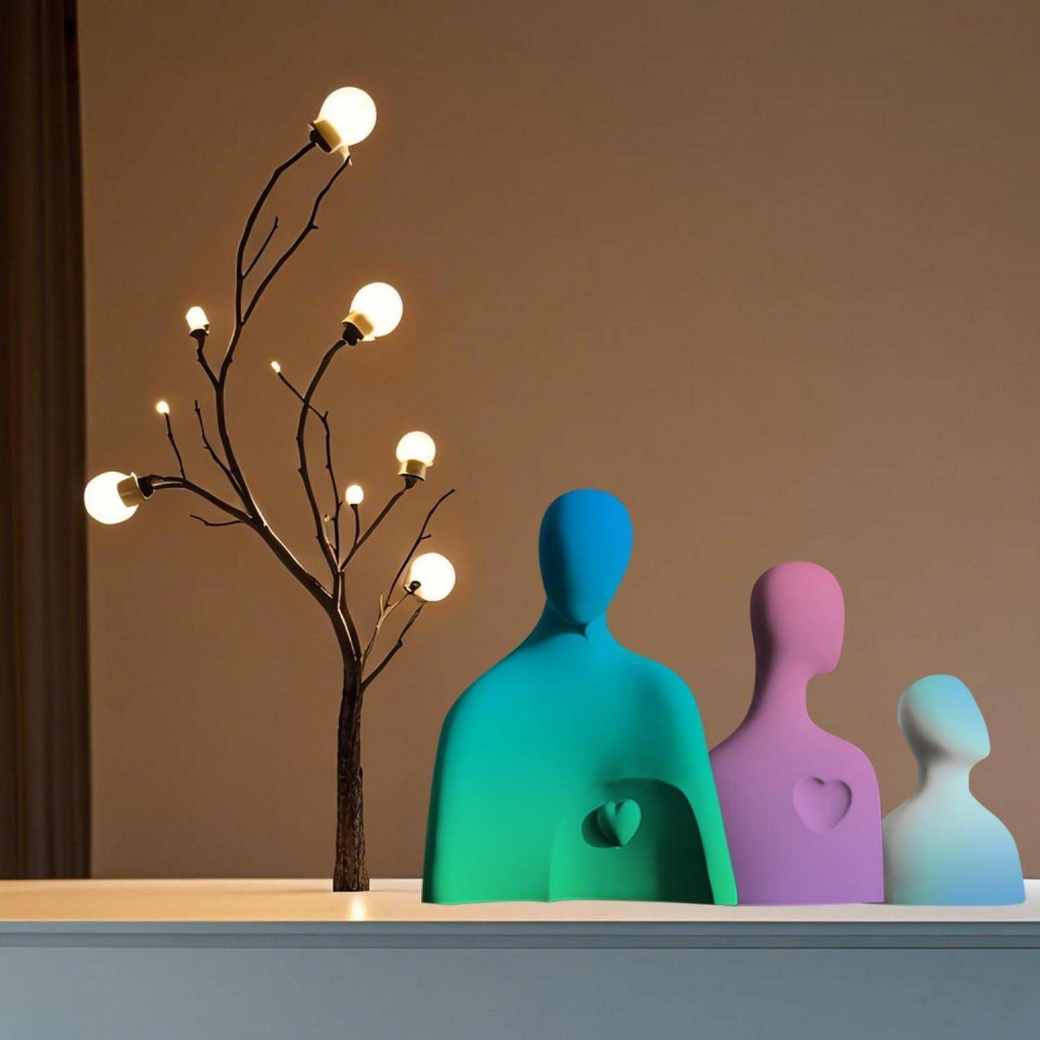 Drei bunte menschenförmige Figuren mit Herzausschnitten sitzen neben einer dekorativen baumartigen Lampe mit leuchtenden Glühbirnen auf einem Regal.