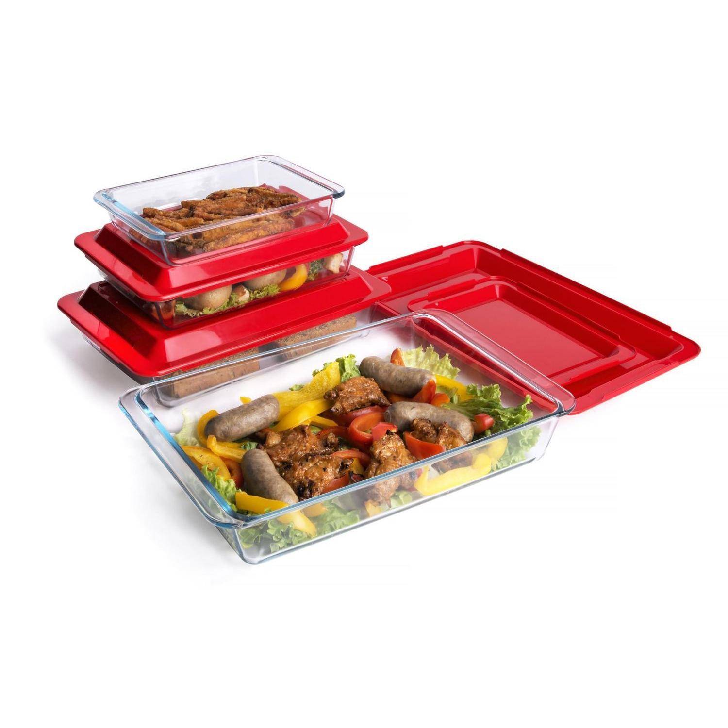 Stapel von Glasspeicher-Behältern mit roten Deckeln, ein offenes Tablett zeigt gekochte Würstchen, Gemüse und Fleisch auf weißem Hintergrund.