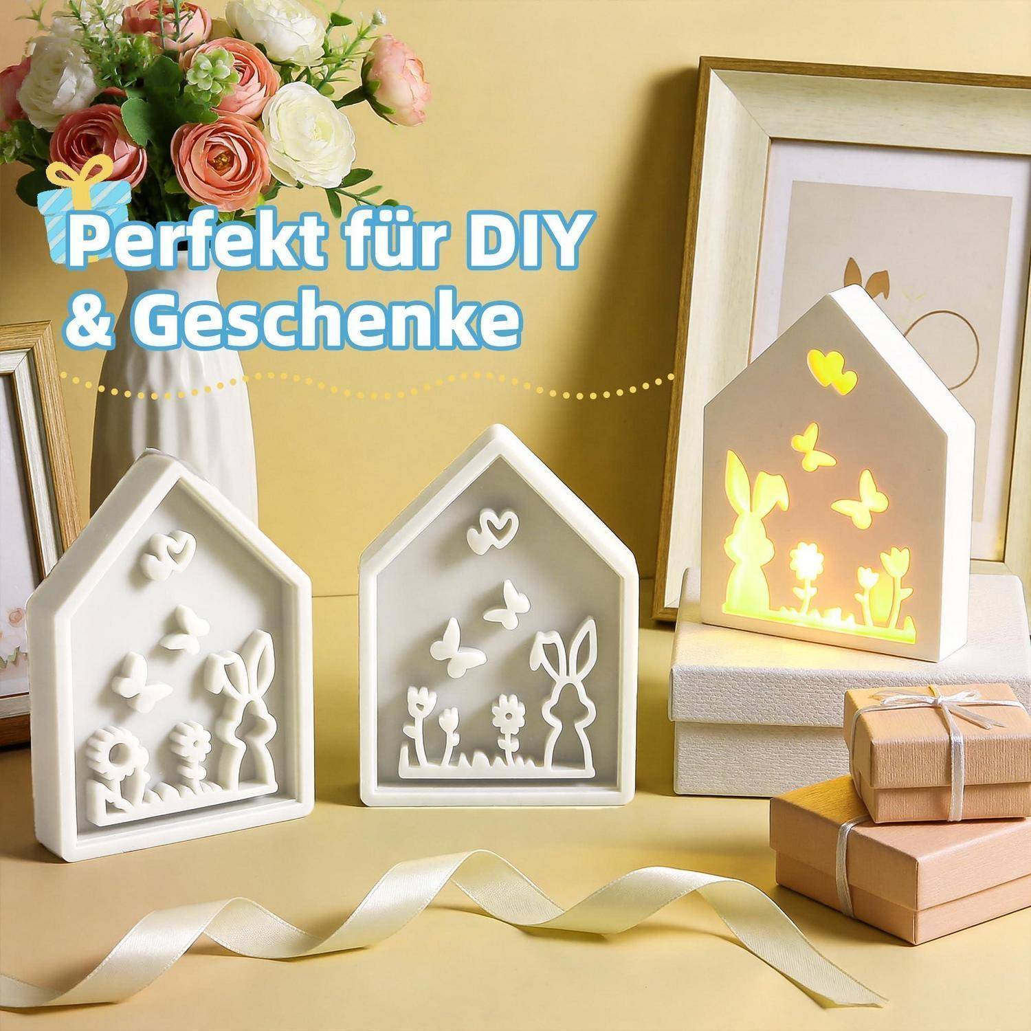Drei hausförmige dekorative Leuchtkästen mit ausgeschnittenen Schmetterlingen und Hasen, einer leuchtet gelb, in einer Geschenkausstellung mit dem Text „Perfekt für DIY & Geschenke