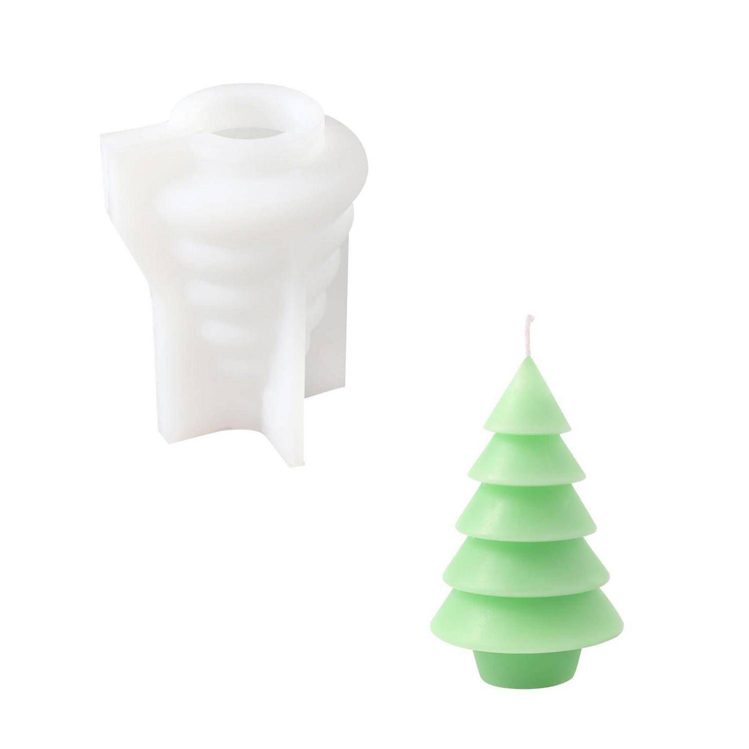 Weißer gefalteter Papierschmuck neben einer kleinen grünen weihnachtsbaumförmigen Kerze auf weißem Hintergrund.