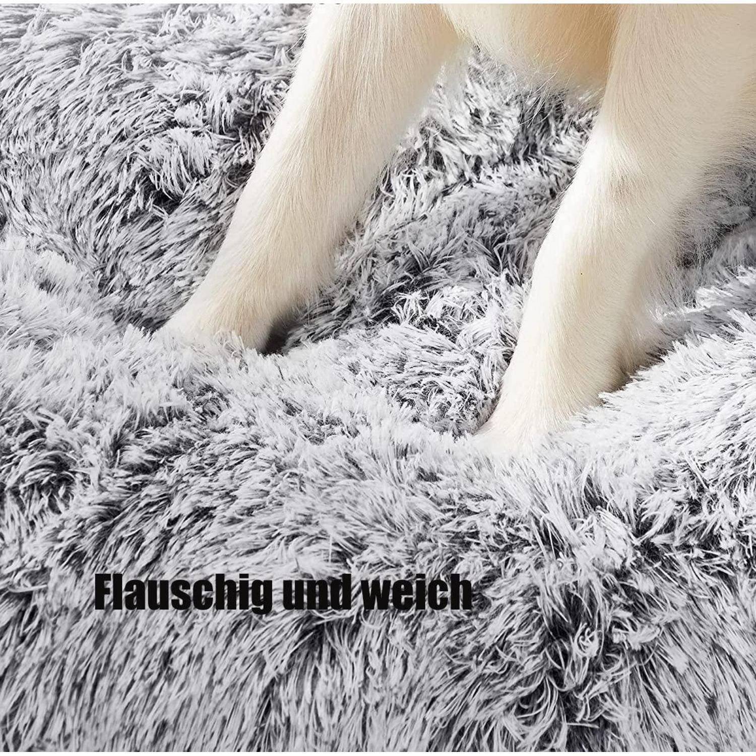 Nahaufnahme der weißen Beine eines Hundes, die auf einer flauschigen grauen Hochflor-Decke stehen, mit dem deutschen Text „Flauschig und weich" in der Nähe des unteren Randes.