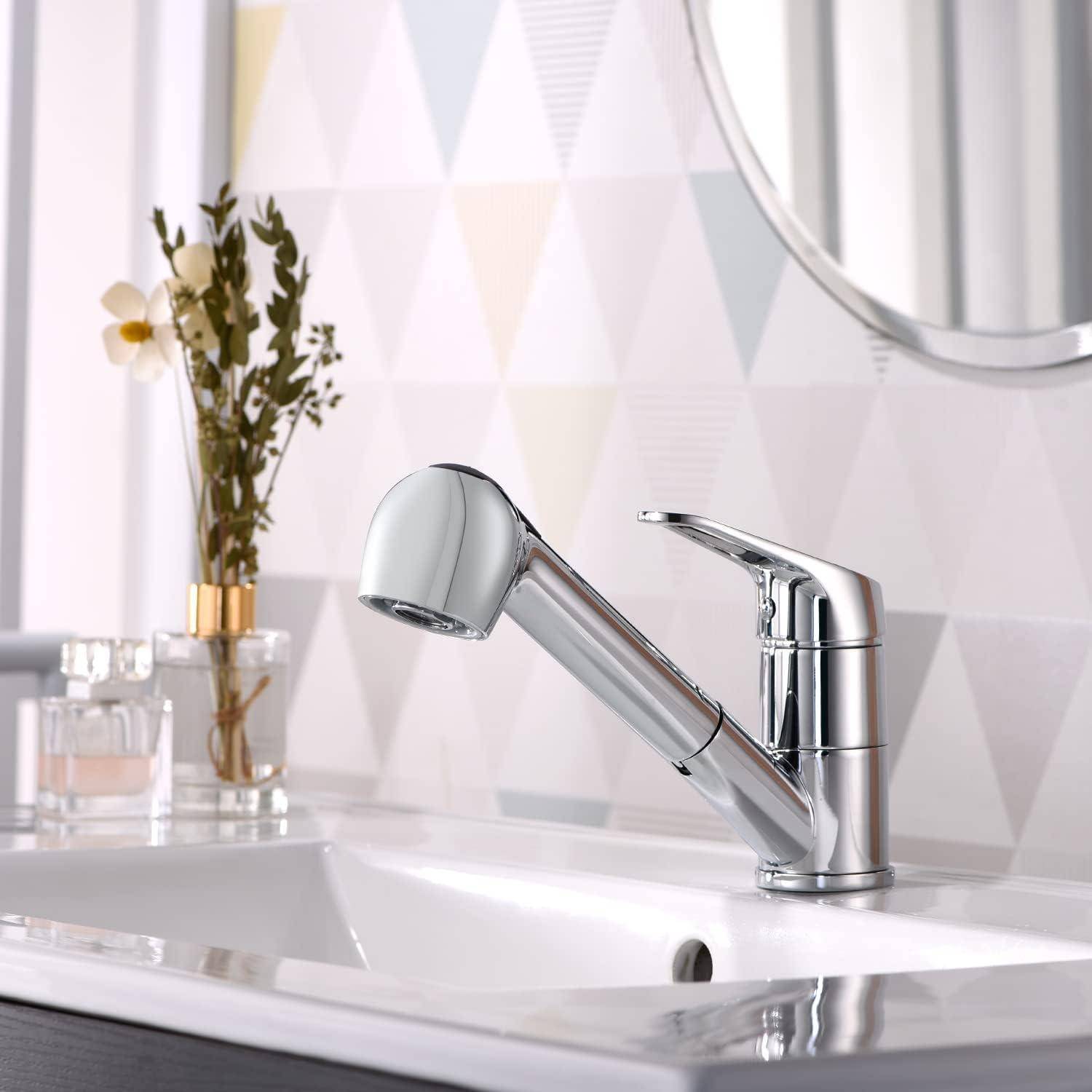 Chromglänzender Badezimmer-Wasserhahn mit ausziehbarem Sprayer auf einem weißen Waschtisch, mit einer Blumenvase und einem teilweise sichtbaren Spiegel im Hintergrund.