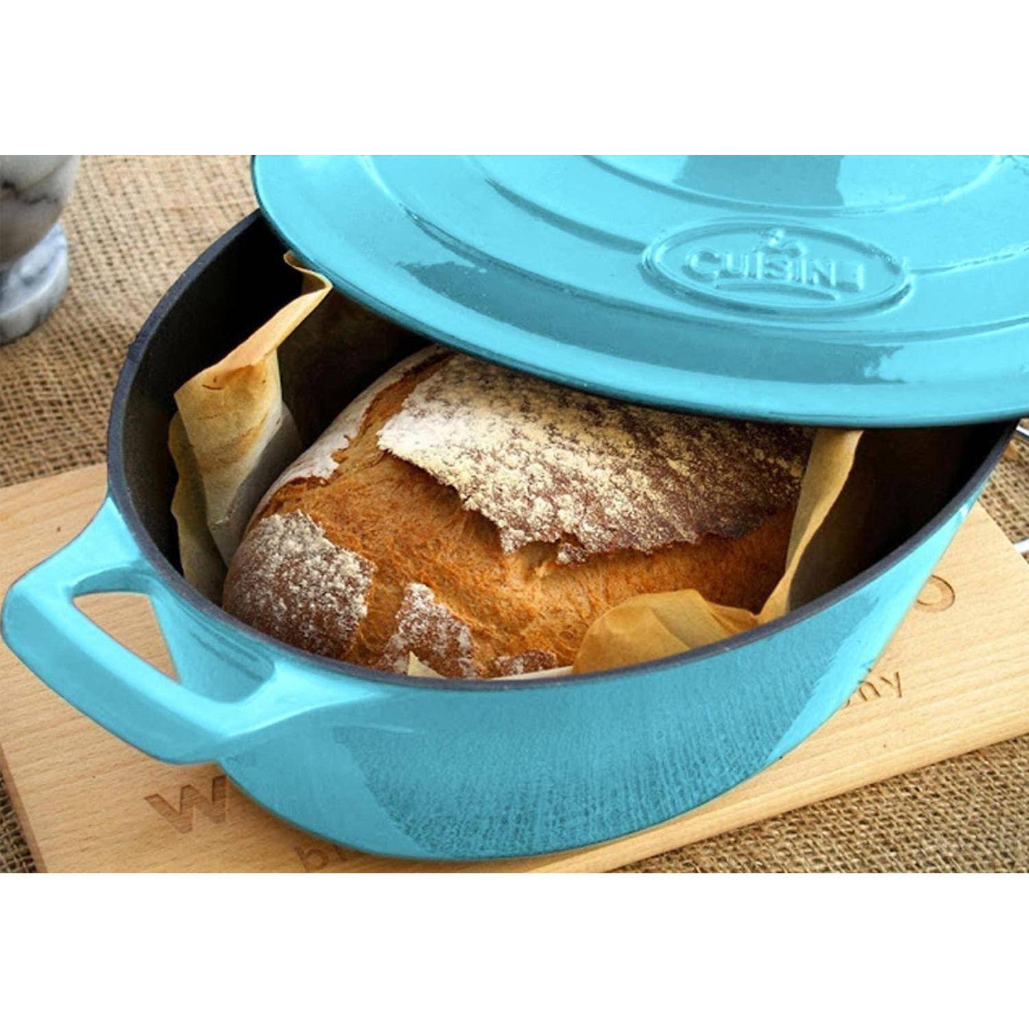 Rundes Brotlaib, das in einem türkisfarbenen Gusseiserntopf mit teilweise geöffnetem Deckel gebacken wurde, ruht auf einem Holzbrett.