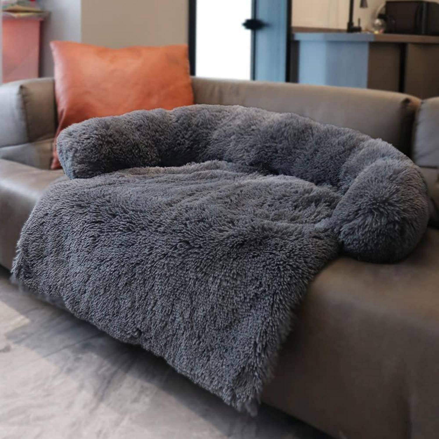 Grausbett aus Plüsch oder eine Decke, die über ein braunes Sofa im Wohnzimmer drapiert ist.