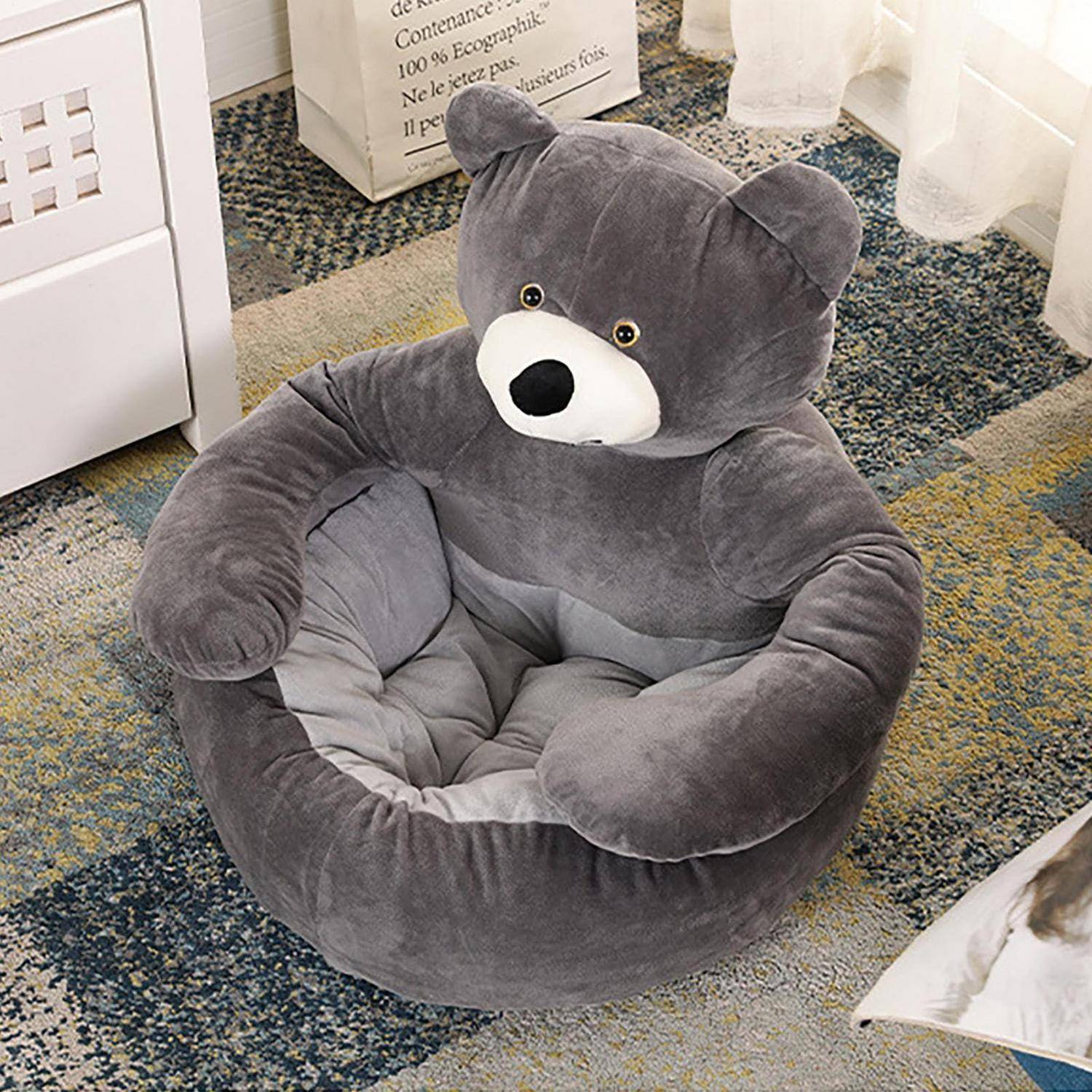 Grausbett aus Plüsch in Teddybärform auf einem gemusterten Teppich neben einem Fenster und Möbeln.