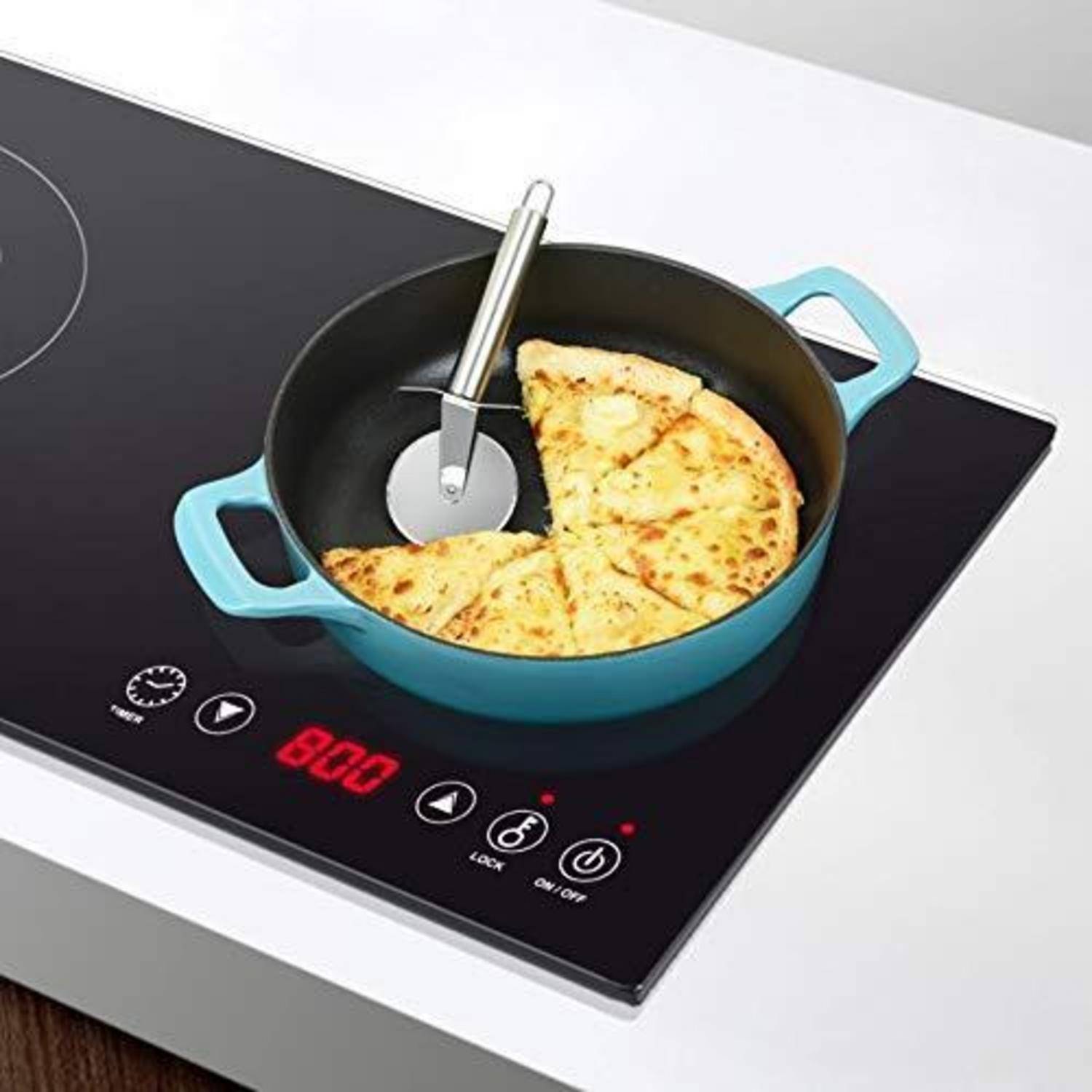 Blauer Topf auf einem Induktionskochfeld mit einem Pizzaschneider, der eine geschnittene Torte oder ein Tortilla-Stück im Inneren schneidet; digitale Bedienelemente sind auf der Kochplatte sichtbar.