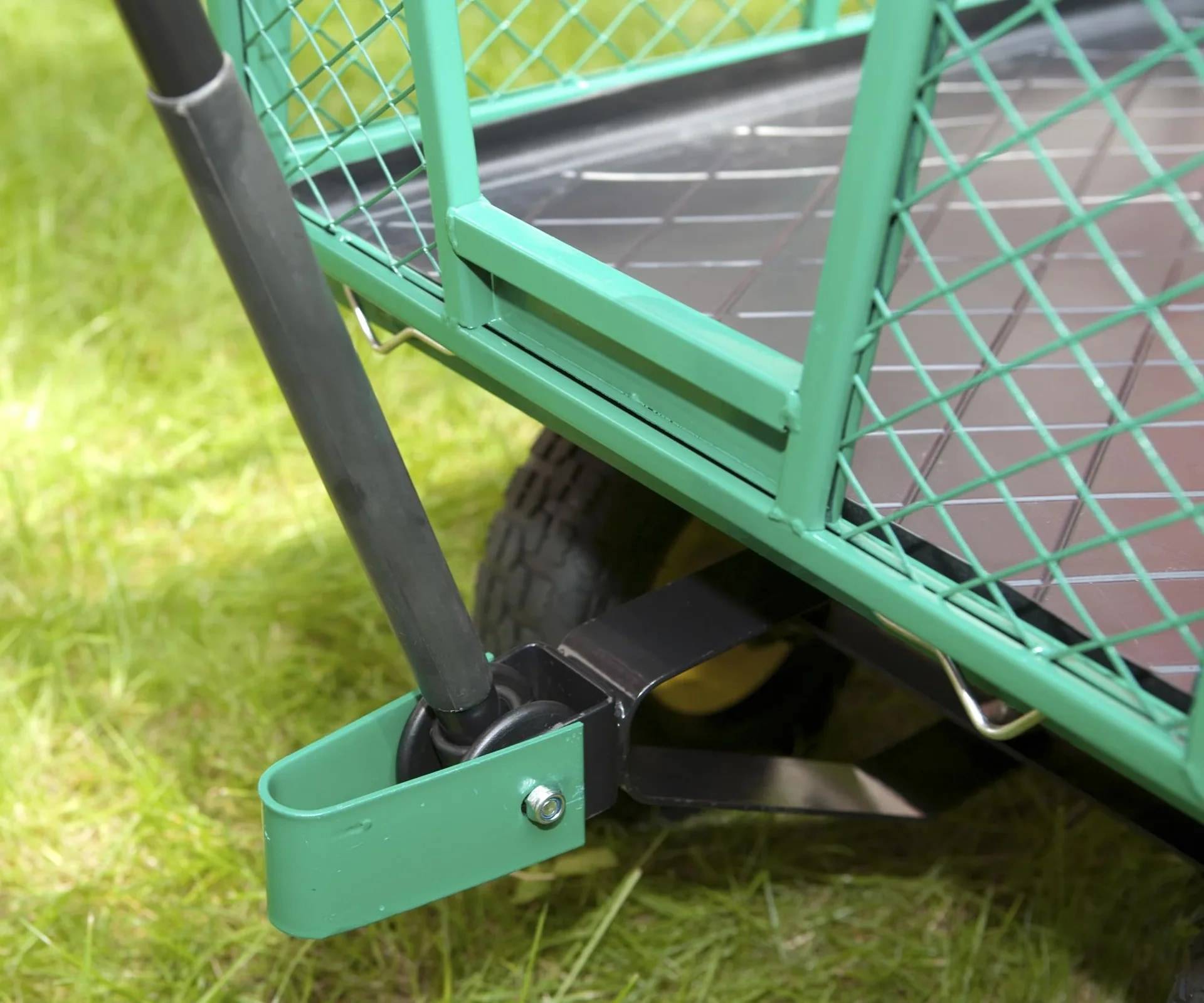 Nahaufnahme einer grünen Metallwagenkupplung und eines Rads auf Gras, das die vordere Verbinderbaugruppe zeigt.