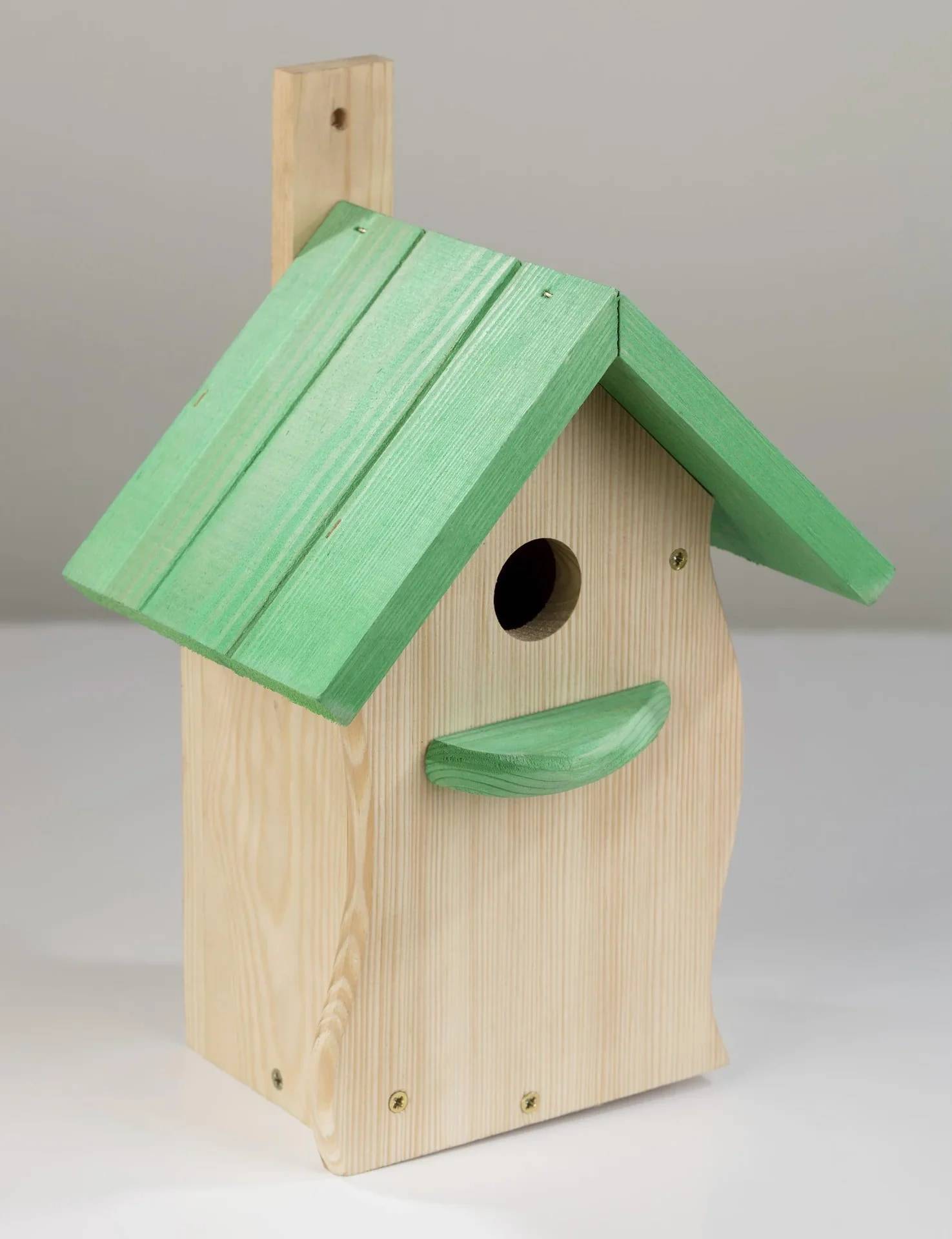 Kleines Vogelhaus aus Holz mit grünem Dach und Anflugstange, gezeigt vor einem neutralen Hintergrund.