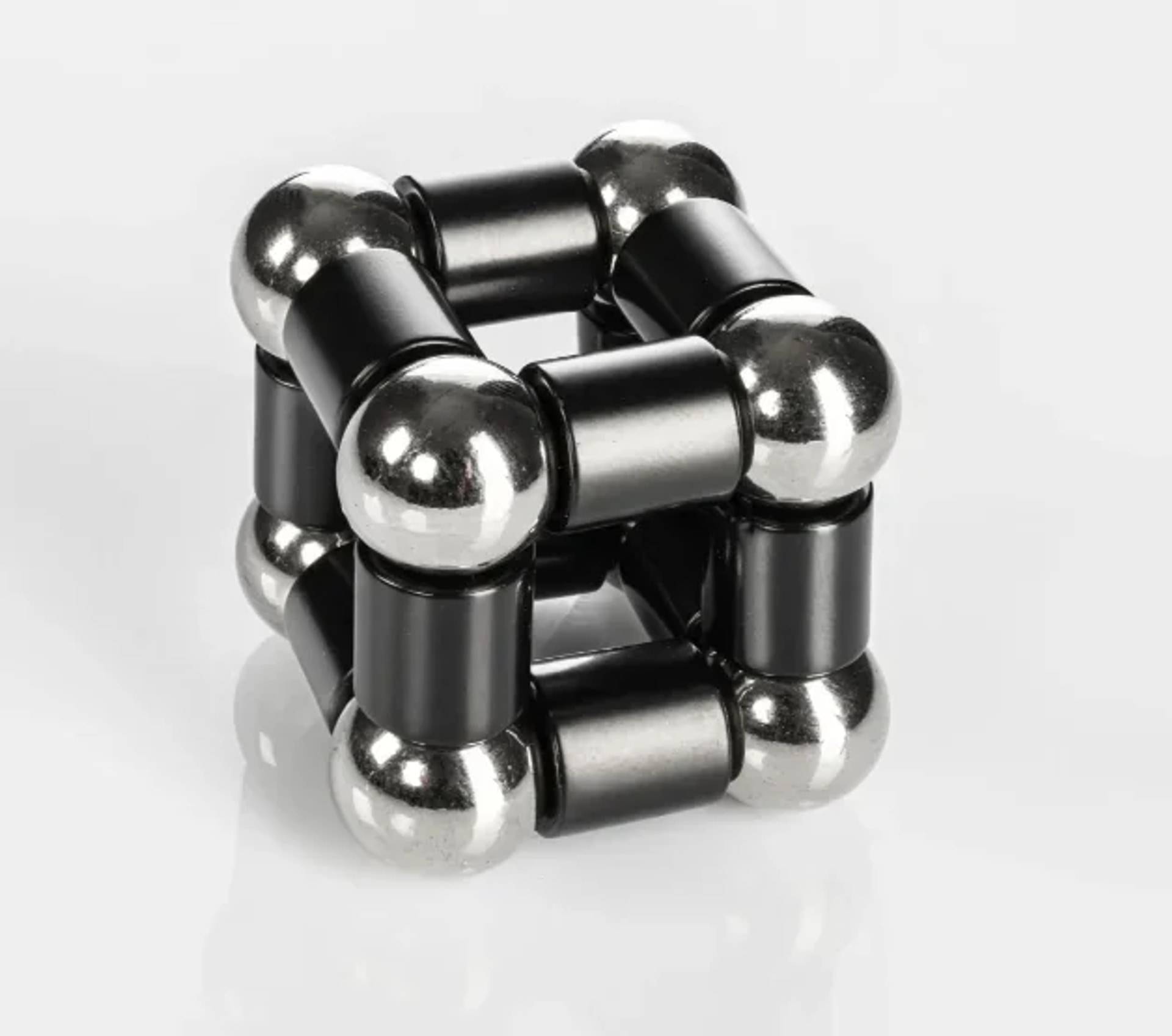 Ein schwarz-silbernes magnetisches Würfelspielzeug aus verbundenen Metallkugeln und -stäben, auf weißem Hintergrund gezeigt.