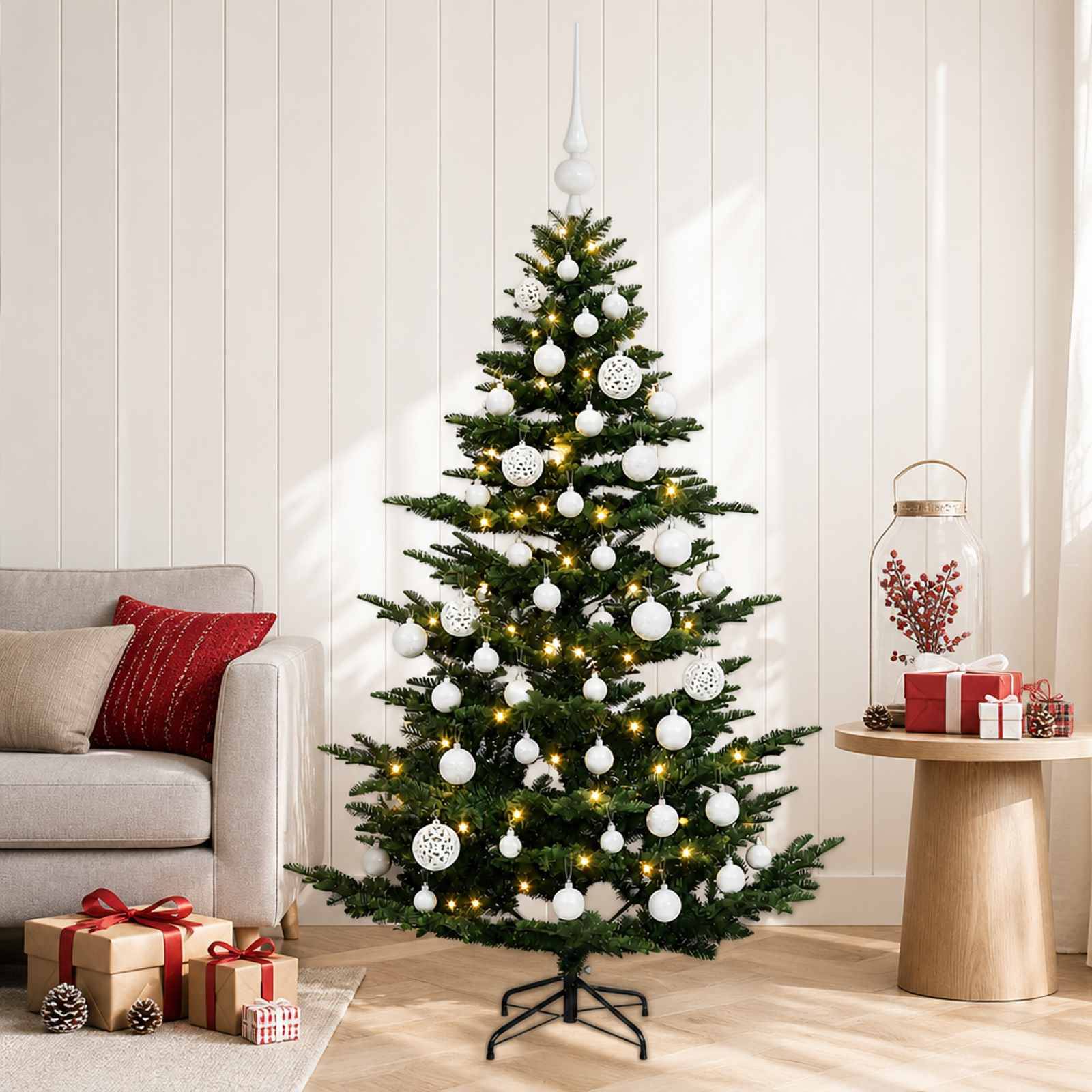 Geschmückter Weihnachtsbaum mit weißen Kugeln und Lichtern in einem Wohnzimmer, mit eingepackten Geschenken in der Nähe und festlicher Dekoration auf einem Beistelltisch.
