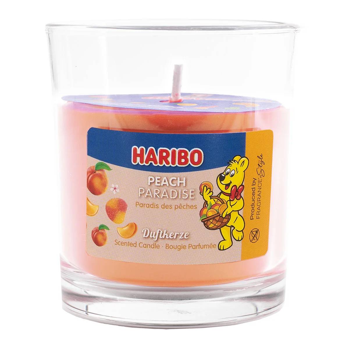 Eine Haribo Peach Paradise duftende Kerze in einem klaren Glaskrug mit pfirsichfarbigem Wachs und Etikett mit dem Haribo-Bären.