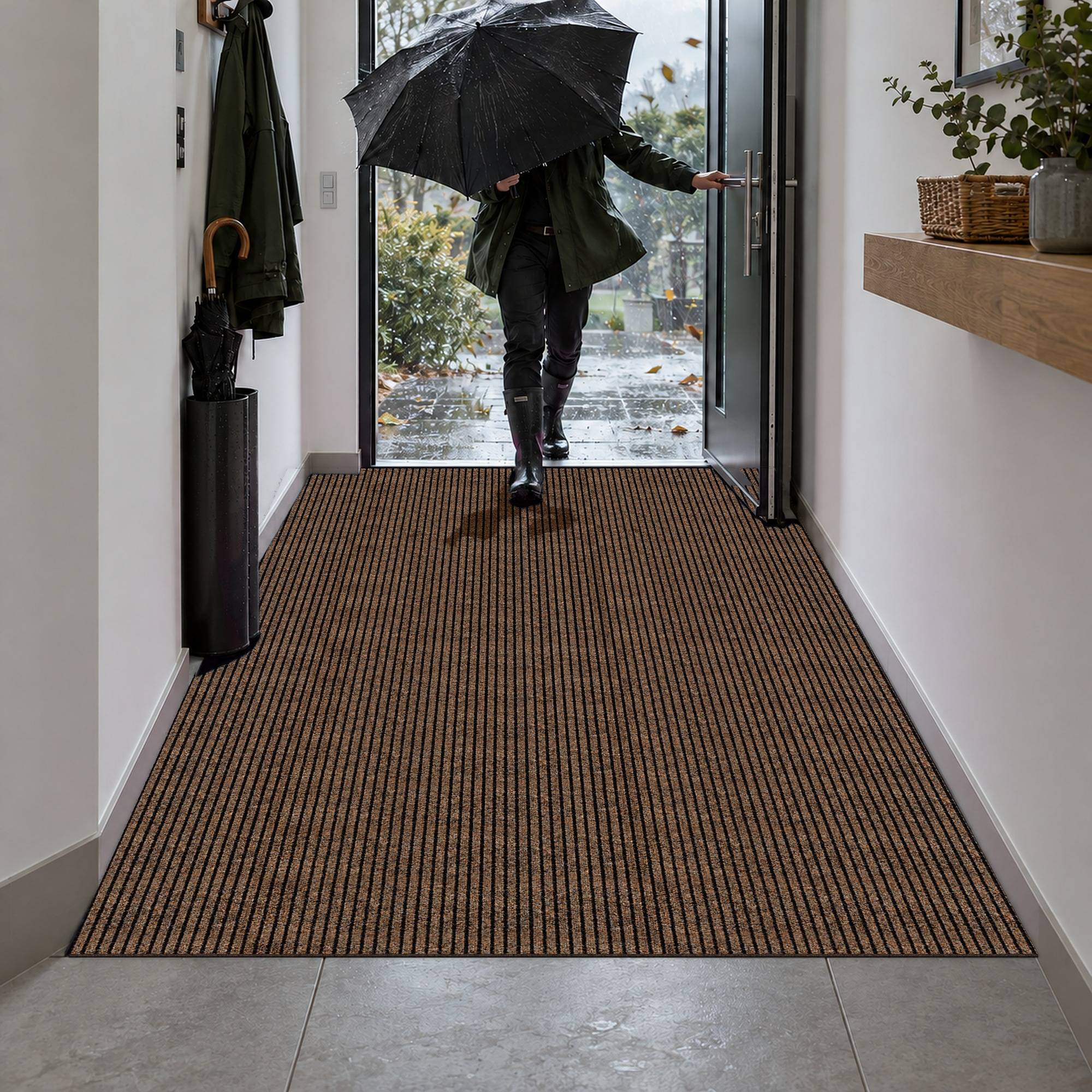 Person mit Regenschirm betritt an einem regnerischen Tag durch die offene Haustür ein Haus und wird vom Flur aus mit braunem Läufer beobachtet.