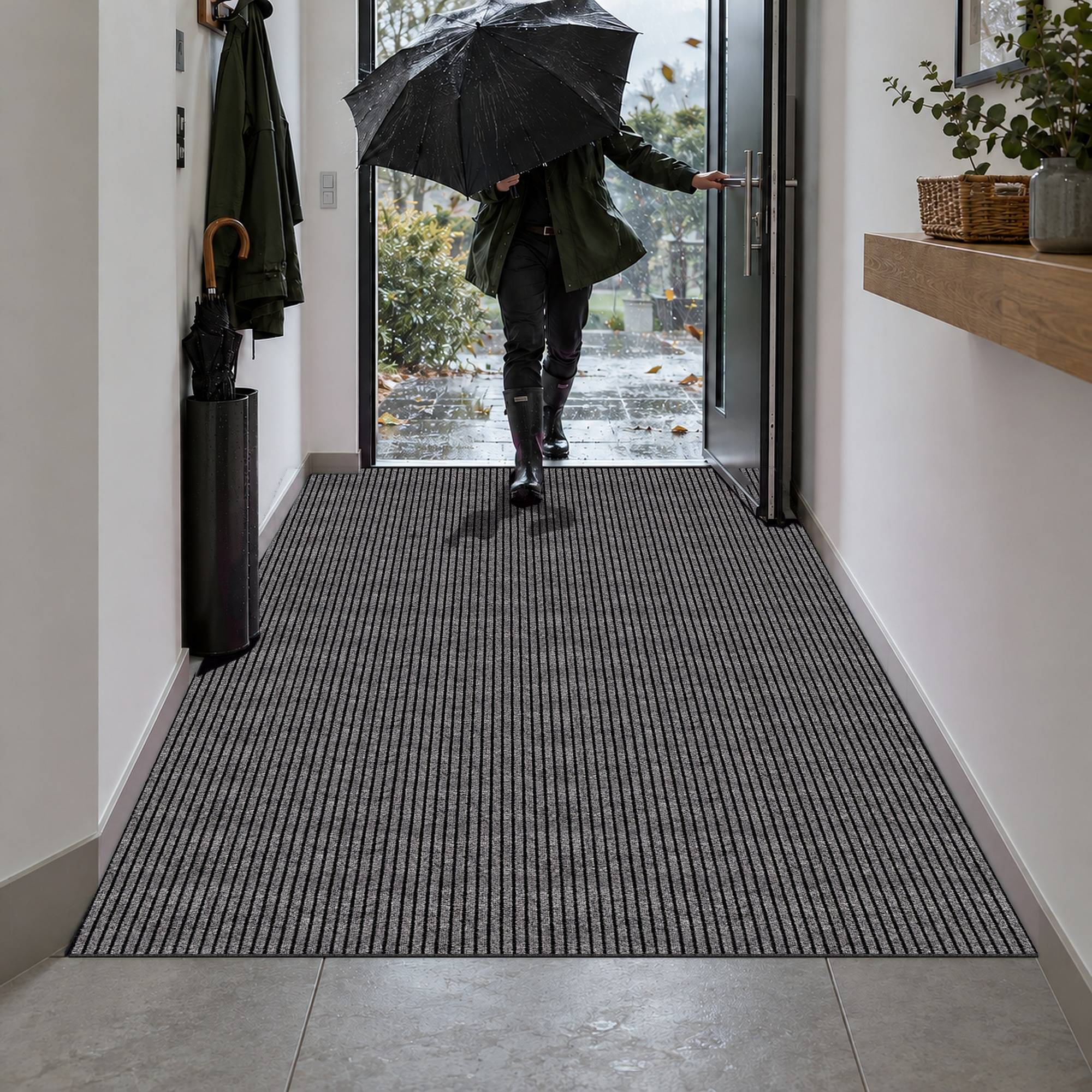 Person mit Regenschirm, die durch eine offene Türöffnung aus einem Flur mit dunklem Streifenteppich in regnerisches Wetter hinausgeht.