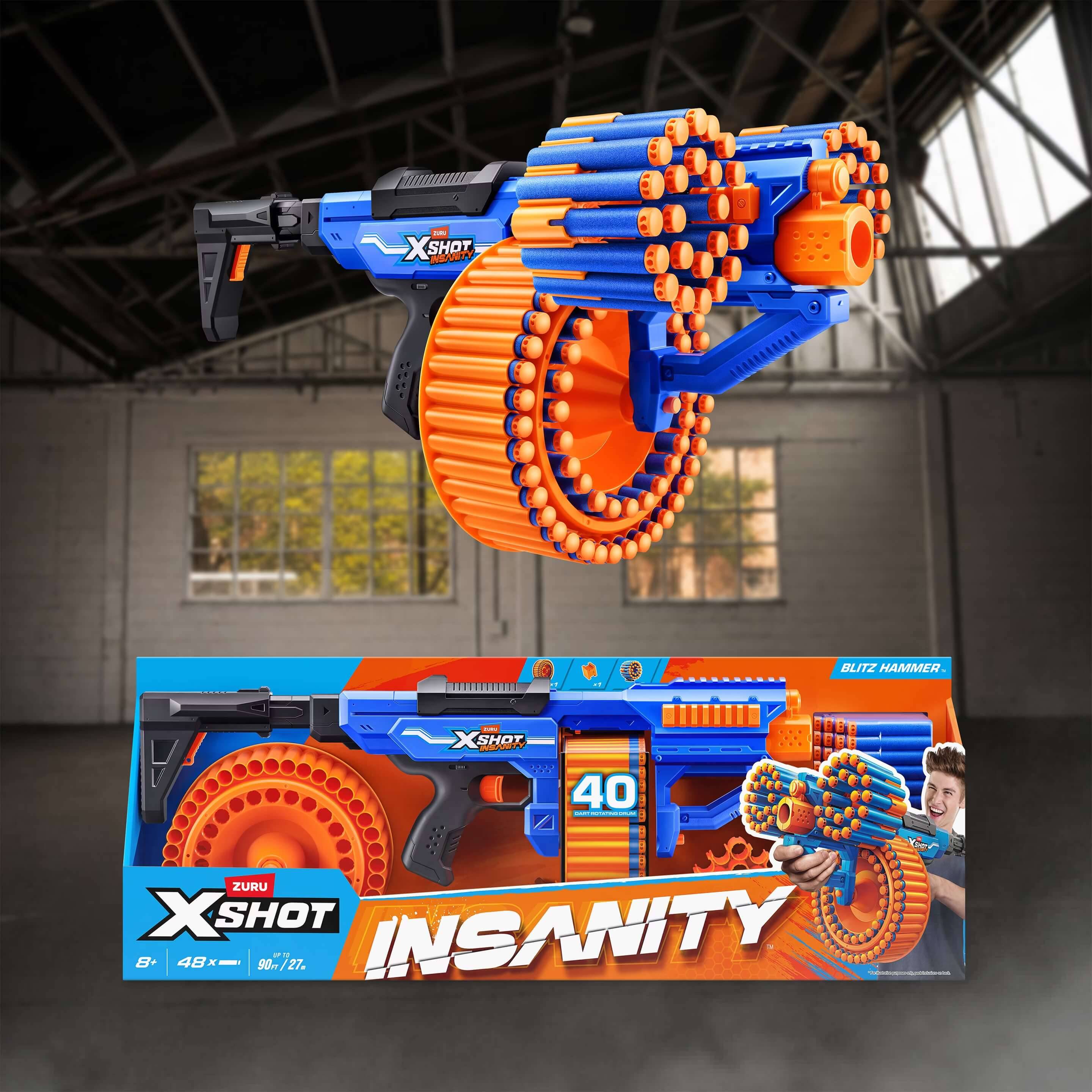 Blau-orangefarbiger XSHOT Insanity Spielzeugblaster mit einer großen kreisförmigen Dartmagazin, abgebildet über seiner Einzelhandelsverpackung in einer lagerartigen Umgebung.