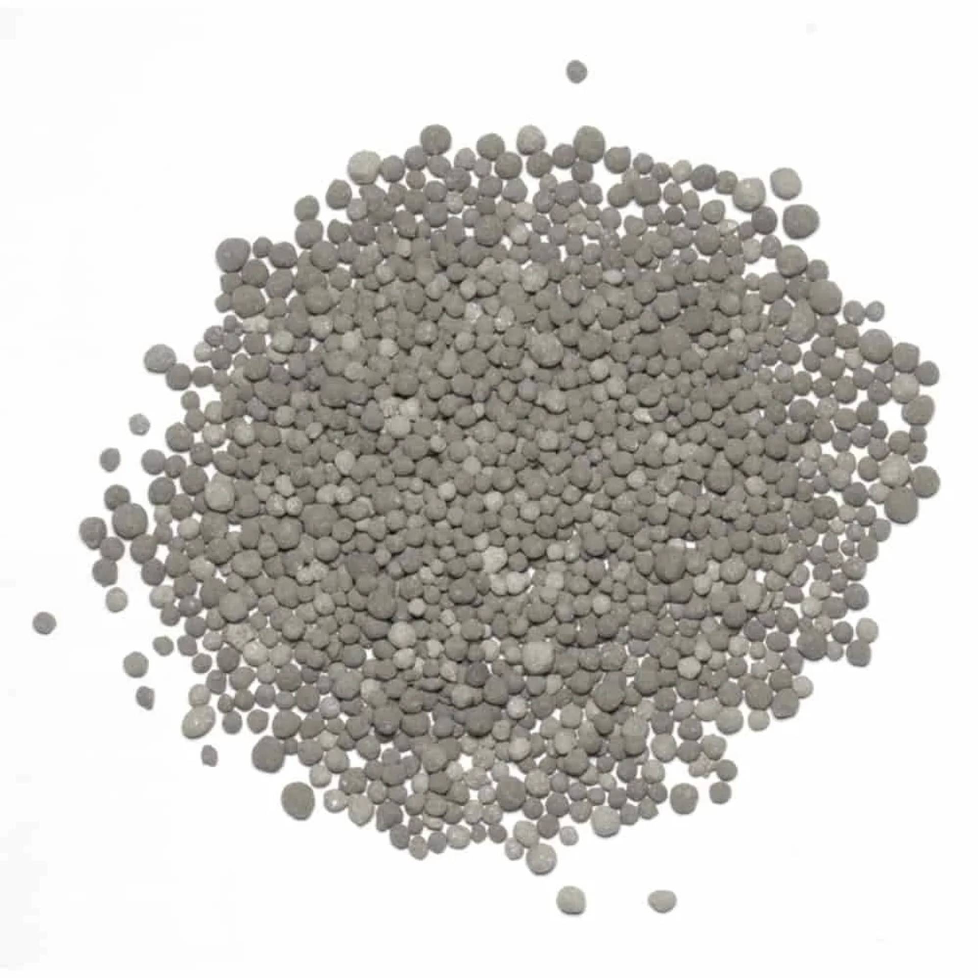 Haufen von kleinen grauen kugelförmigen Pellets, die auf weißem Hintergrund verstreut sind.