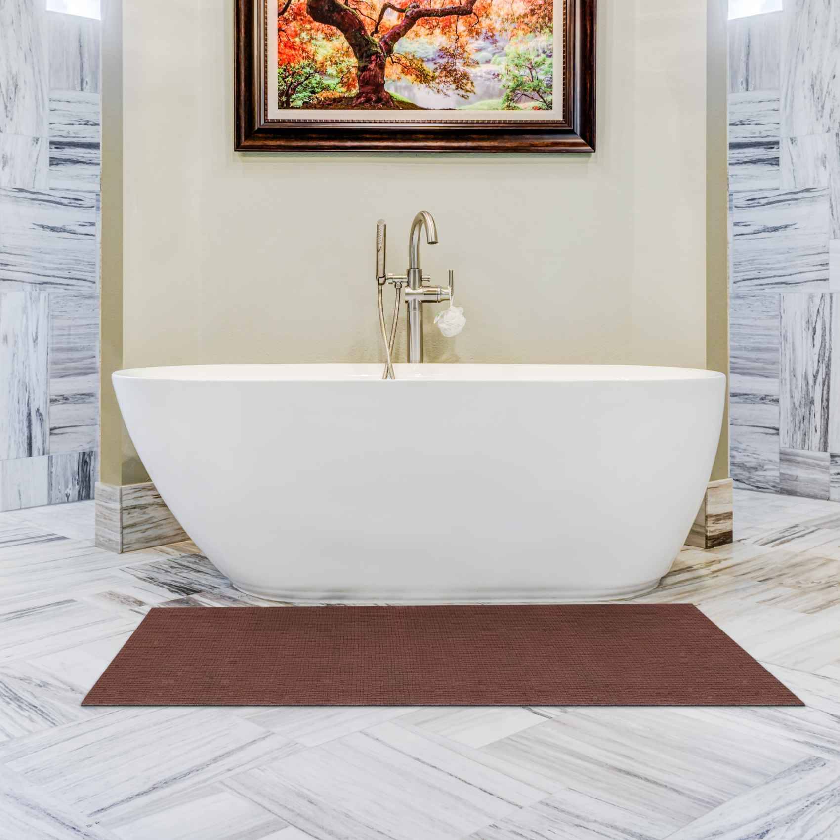 Modernes Badezimmer mit einer freistehenden weißen ovalen Badewanne, die unter einem gerahmten Baumbild zentriert ist, flankiert von Marmor-Wänden und Boden, mit einer braunen Badmatte davor.