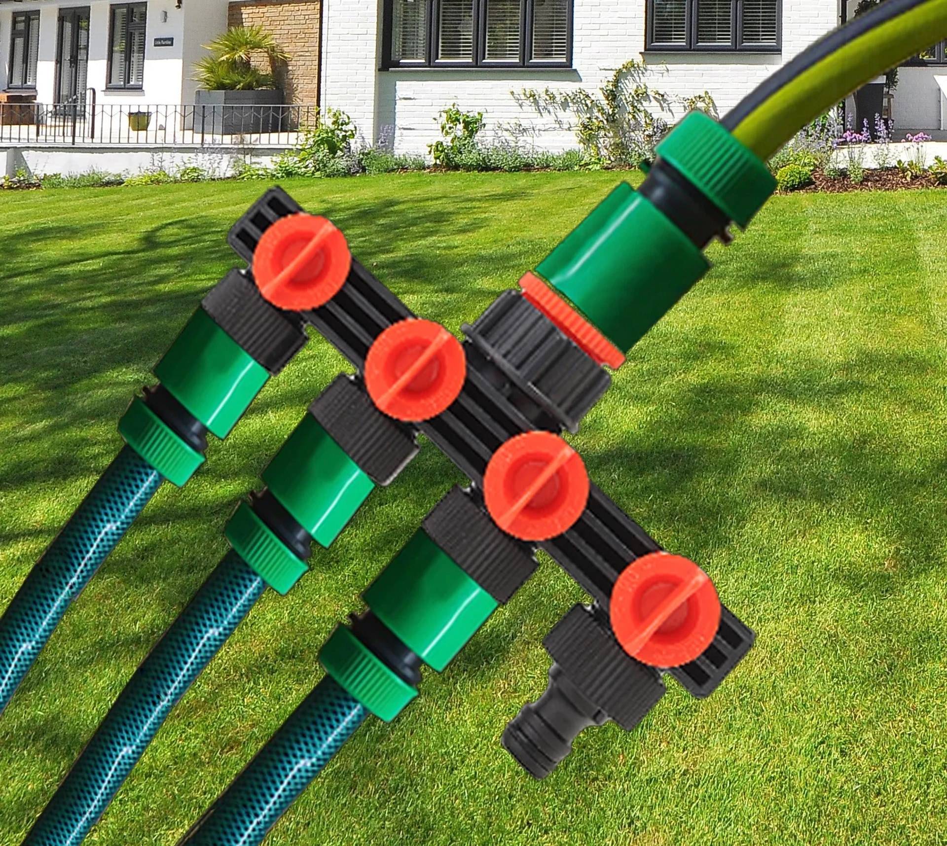Nahaufnahme eines Gartenschlauch-Verteilers mit vier orangefarbenen Absperrventilen, die mehrere Schläuche auf einem Rasen verbinden.