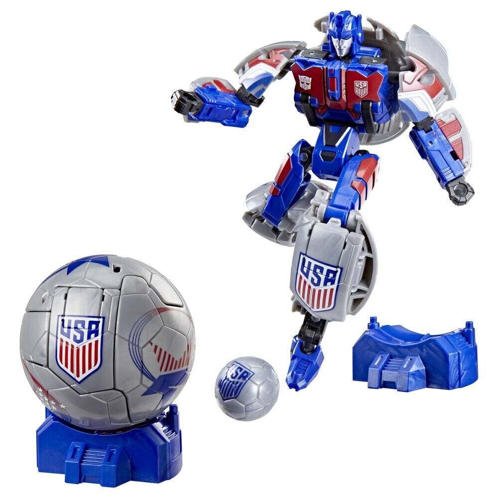 Transformierendes blau-silbernes Roboter-Spielzeug mit USA-Schild-Insignie, gezeigt mit fußballartigen Kugelteilen und einer separaten Zubehörbasis auf weißem Hintergrund.