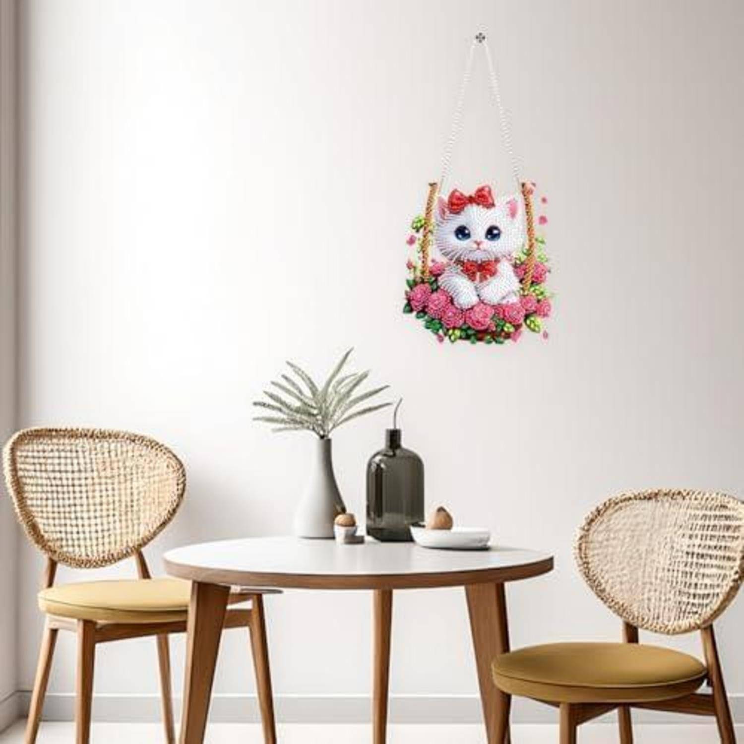 Helle Essecke mit zwei Korbstühlen und einem runden Tisch unter einer hängenden Katzenfloralen-Dekoration an einer weißen Wand.