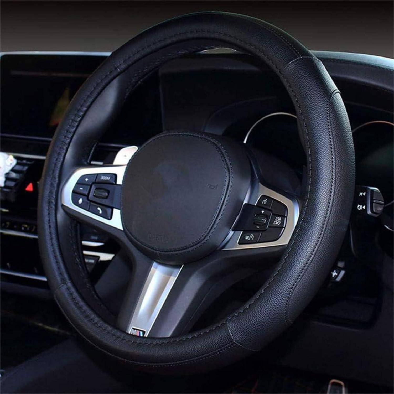 Nahaufnahme eines Autolenkrads mit integrierten Steuertasten, aus der Perspektive des Fahrerplatzes in einem dunklen Innenraum aufgenommen.