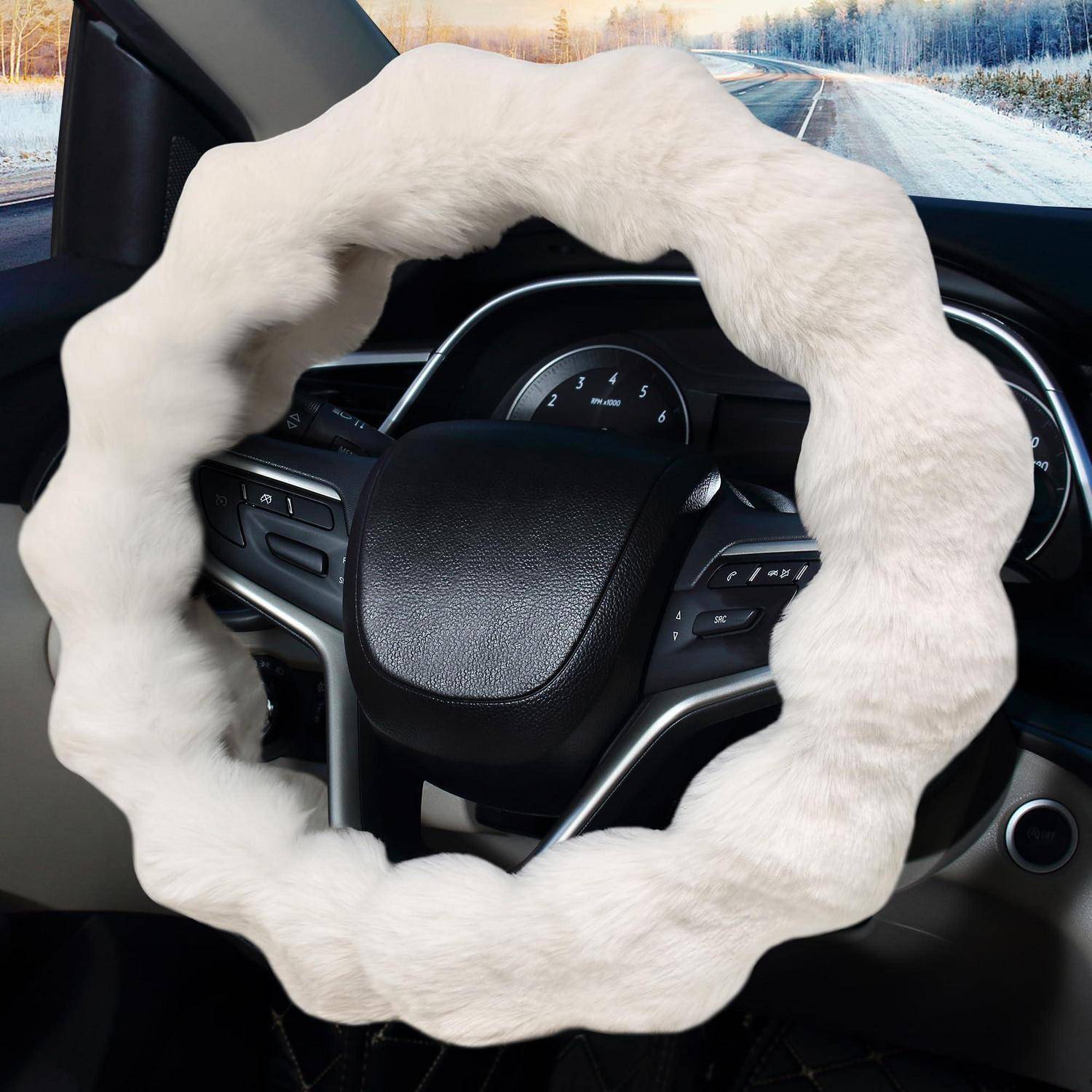 Autolenkrad mit weißem Pelzbezug in einem Fahrzeug, das auf einer Winterstraße fährt.