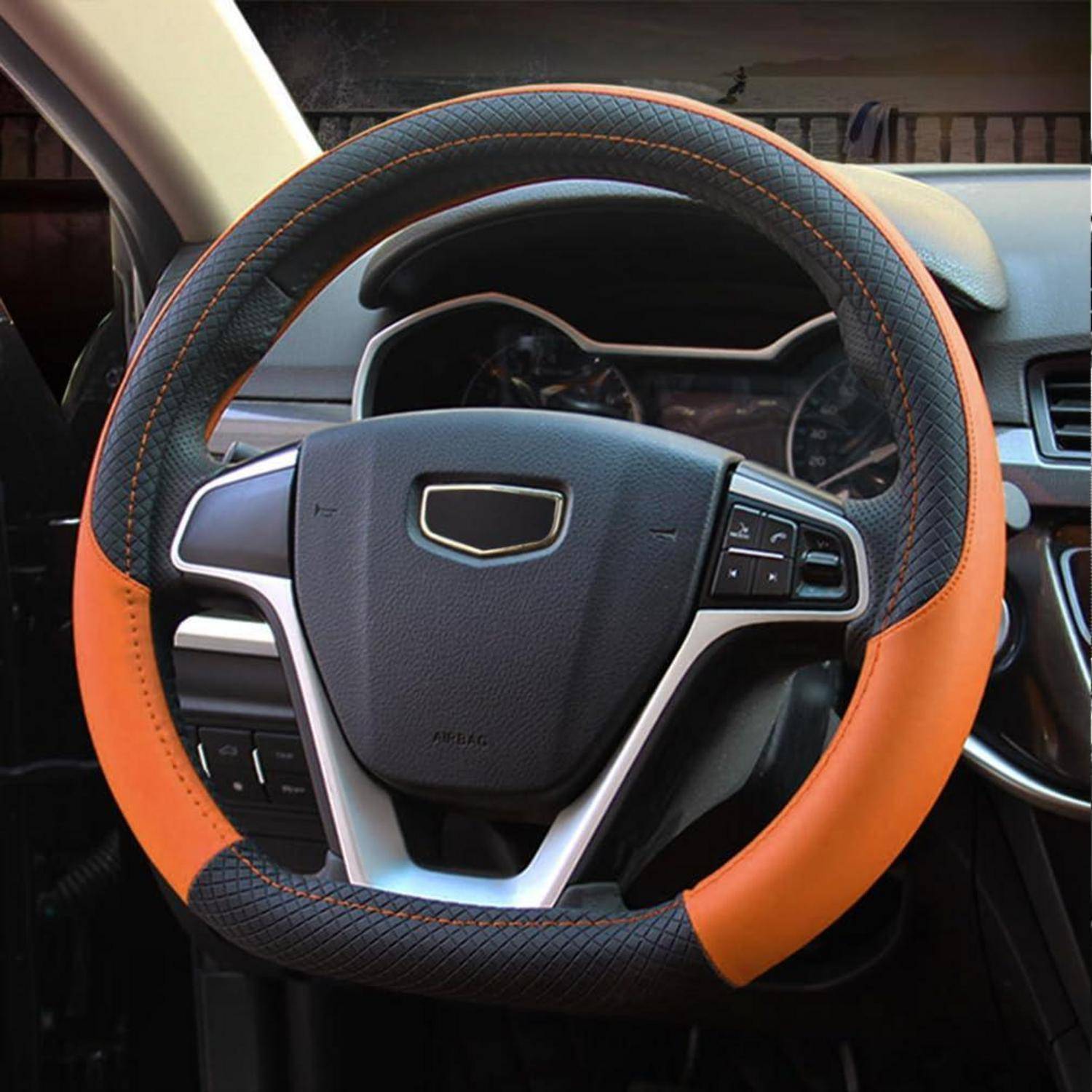 Nahaufnahme eines Autolenkrads mit einer schwarz-orangen Abdeckung und integrierten Steuertasten, aus der Perspektive des Fahrerplatzes betrachtet.