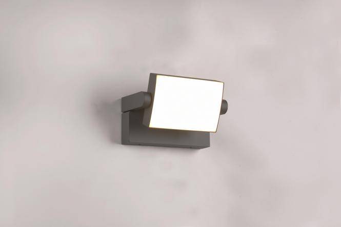 An der Wand montierte quadratische Leuchte mit weißer beleuchteter Frontseite und dunkelgrauem Gehäuse an einer schlichten Wand.