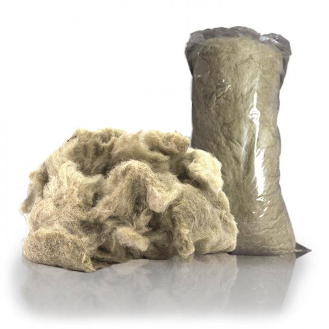 Lose beige Wollefasern neben einem versiegelten Kunststoffbeutel mit ähnlicher Wolle auf weißem Hintergrund.