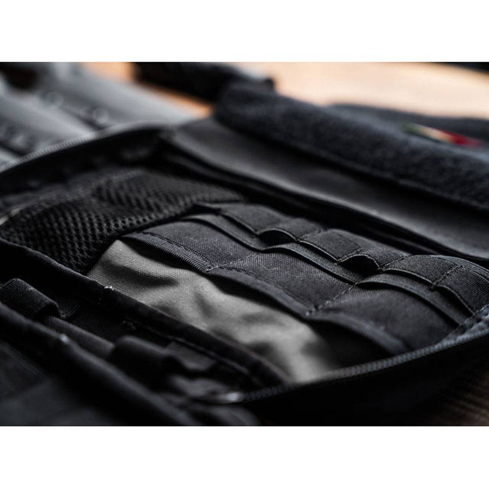 Nahaufnahme eines schwarzen taktischen Weste oder Ausrüstungspanels mit Webbing und Taschen, flach auf einer Oberfläche ausgelegt.