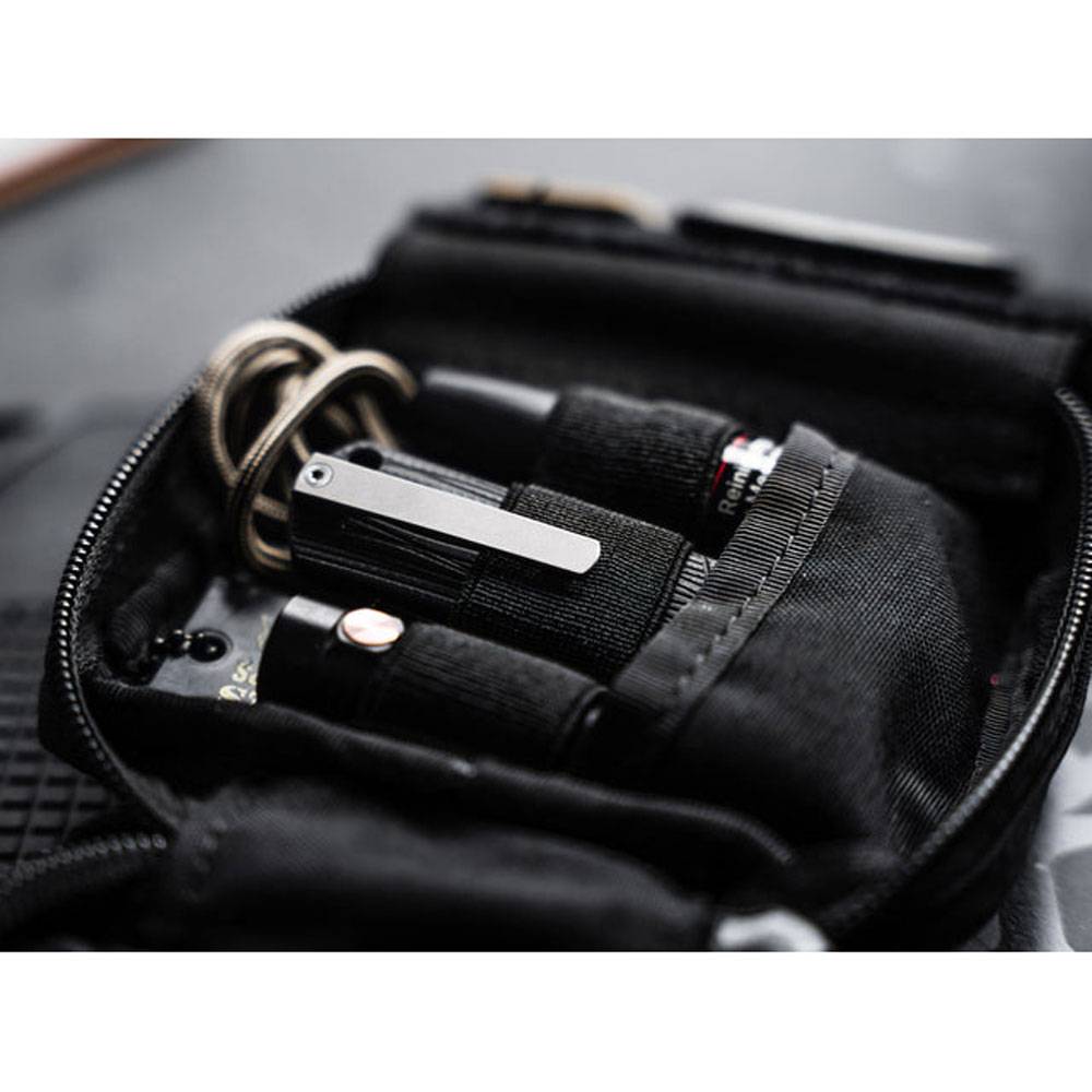 Offene schwarze Reißverschlusstasche mit Schlüsselring und kompakter Taschenlampe oder Multitool, organisiert in elastischen Riemen.