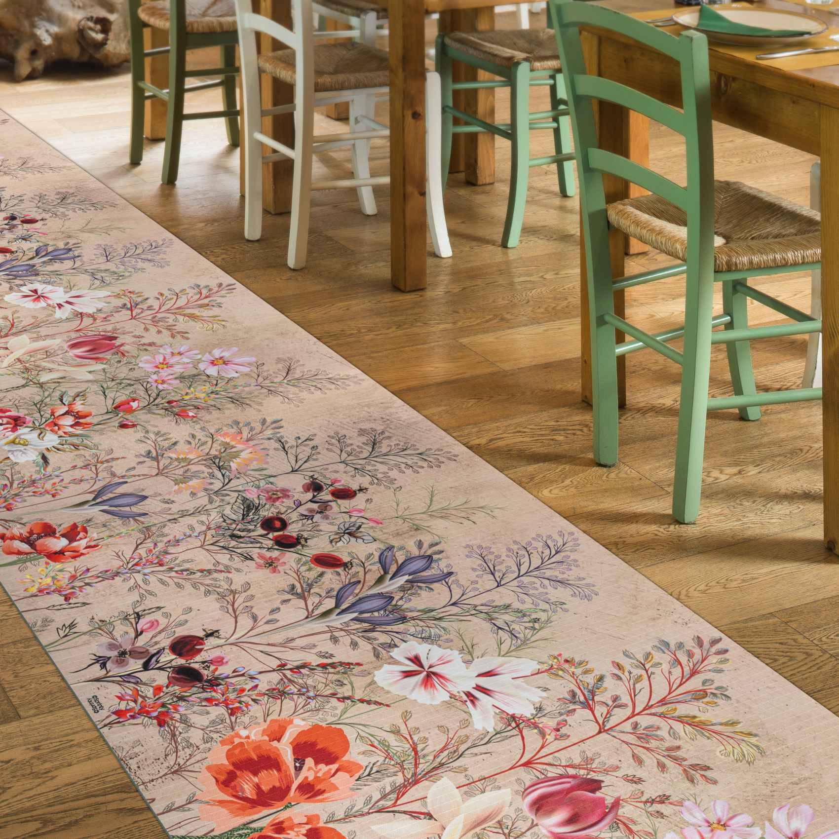 Teppichläufer mit Blumenmuster, bunte Vögel und Blüten auf einem Holzboden neben Esszimmerstühlen und Tischbeinen.