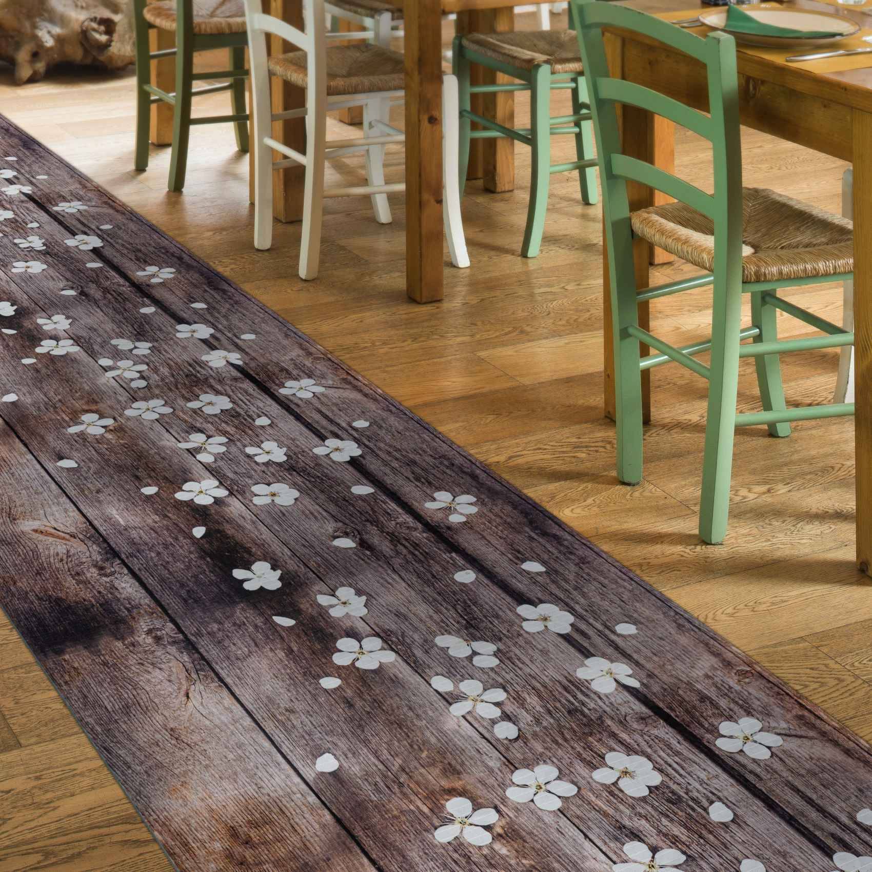 Holztisch für das Esszimmer mit weißem Blumenmuster neben nicht übereinstimmenden bemalten Stühlen auf einem Hartholzboden