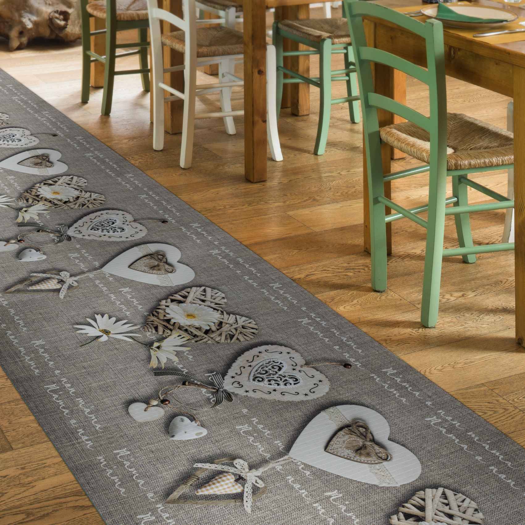 Holzessstühle um einen Tisch auf einem Hartholzboden, neben einem grauen Läufer mit herzförmigen Motiven und Schmetterlingen.