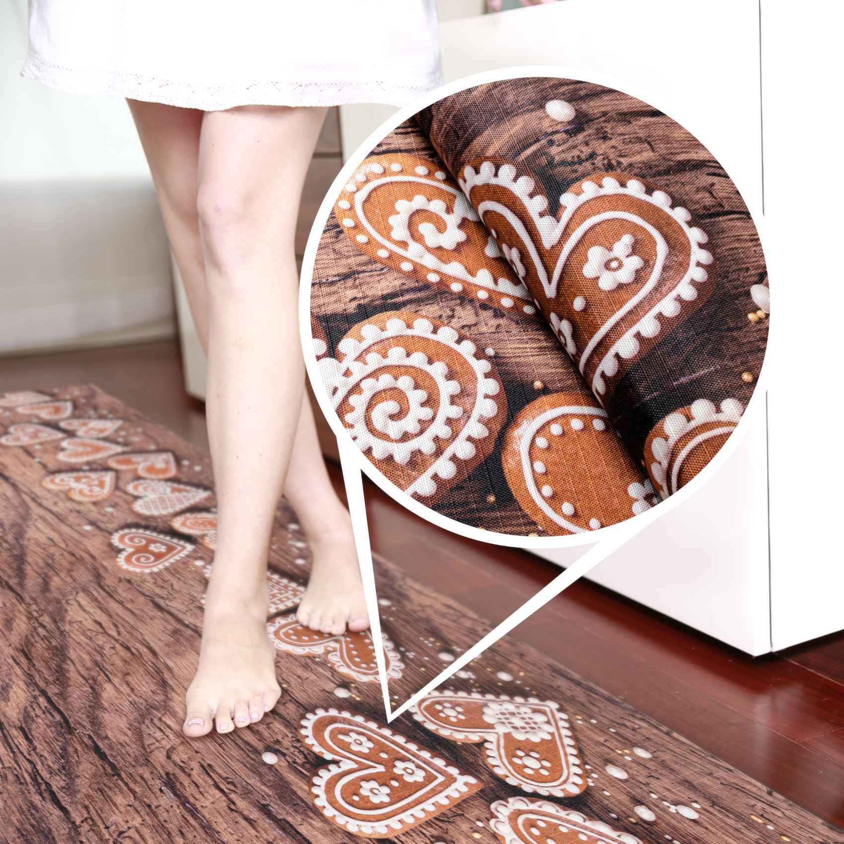Frau, die barfuß auf einer Fußmatte mit Lebkuchen-Muster steht, mit einer kreisförmigen Vergrößerung, die das braun-weiße Herz- und Wirbel-Design aus nächster Nähe zeigt.