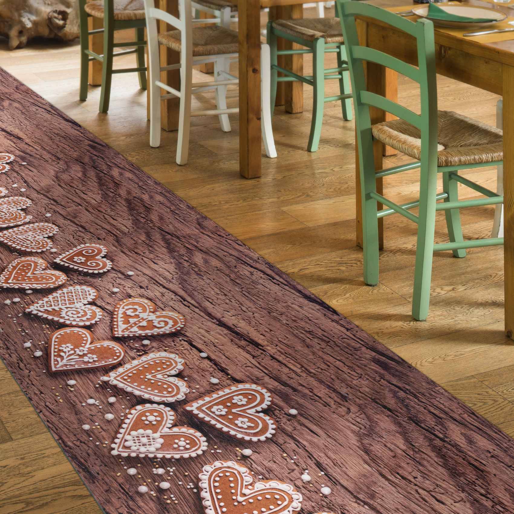 Reihe von dekorierten herzförmigen Keksen auf einem rustikalen Holztisch in einem Café oder Essbereich mit Pastell-Stühlen im Hintergrund.