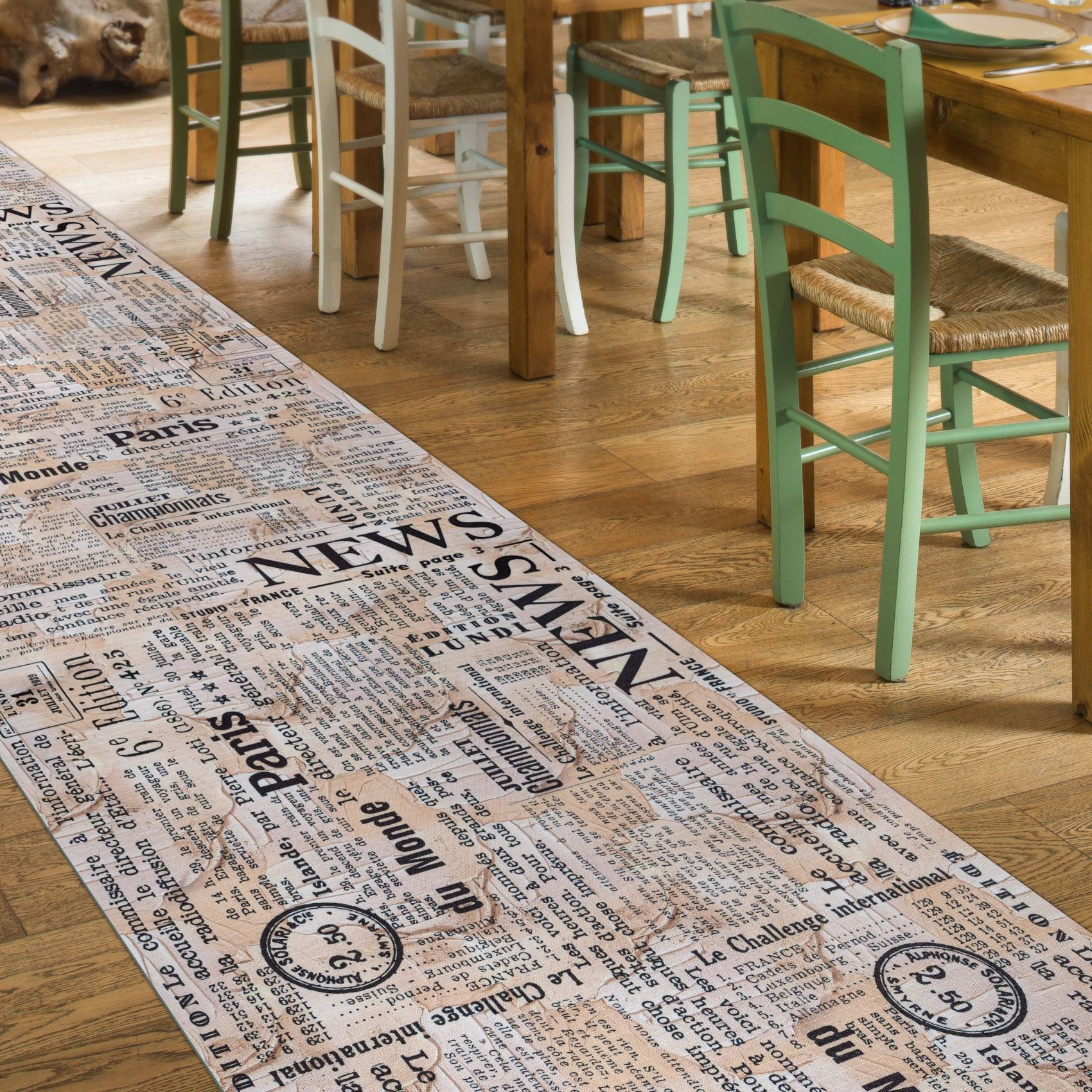 Holztische im Café-Stil und bunte Stühle auf einem Hartholzboden neben einem Flächenteppich mit Zeitungsdruck.